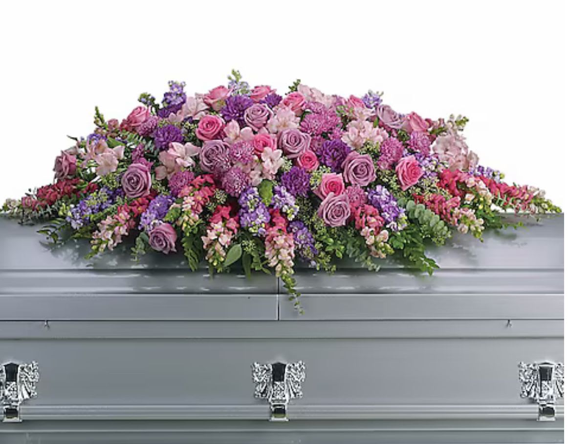 Large pink and purple floral casket spray on a gray casket