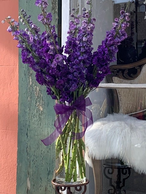 Purple flower bouquet in a clear glass vase with a ribbon bow
