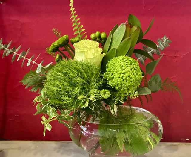Green floral arrangement in a clear glass bowl vase
