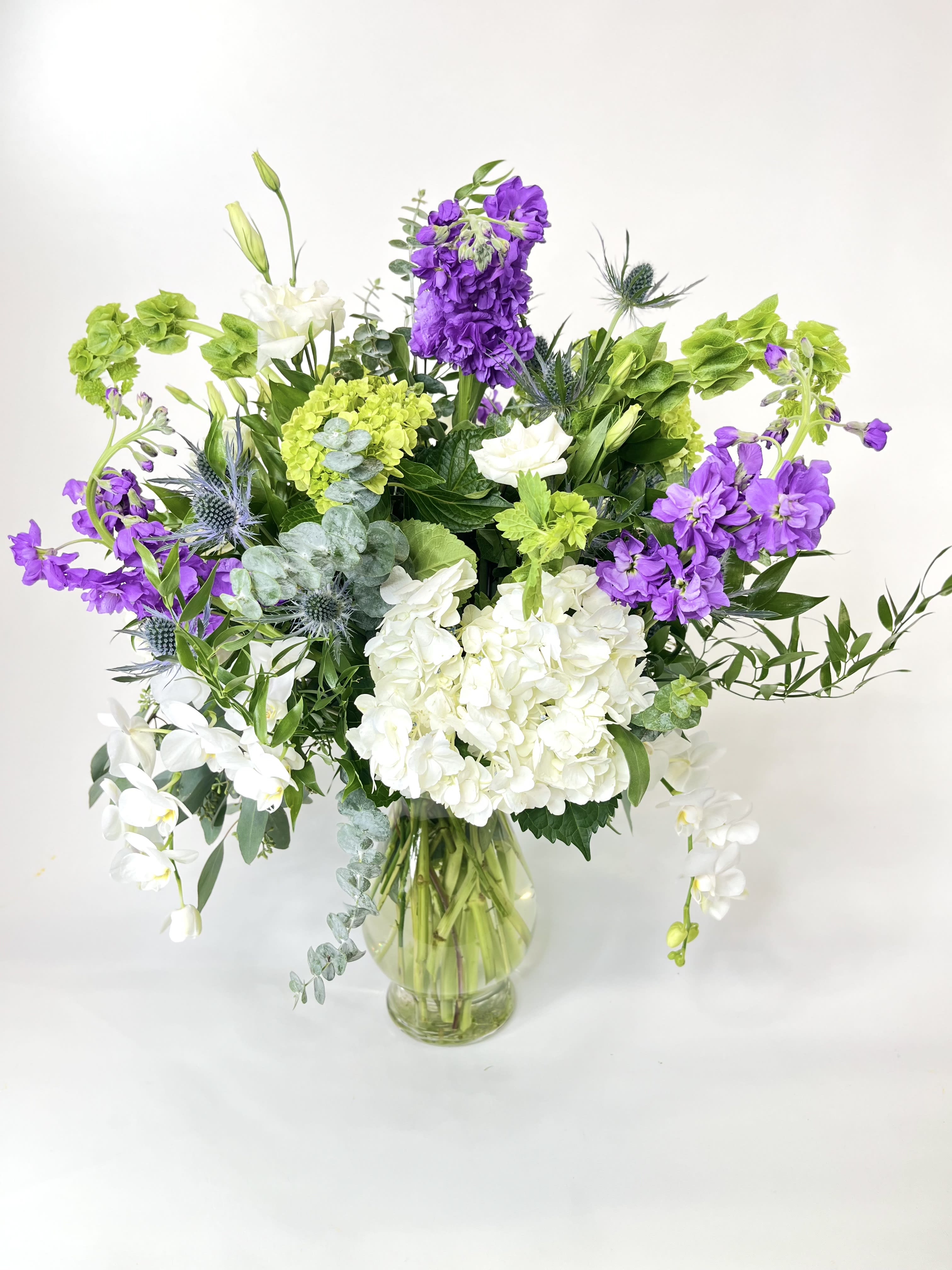 Purple and white flowers arranged in a clear glass vase