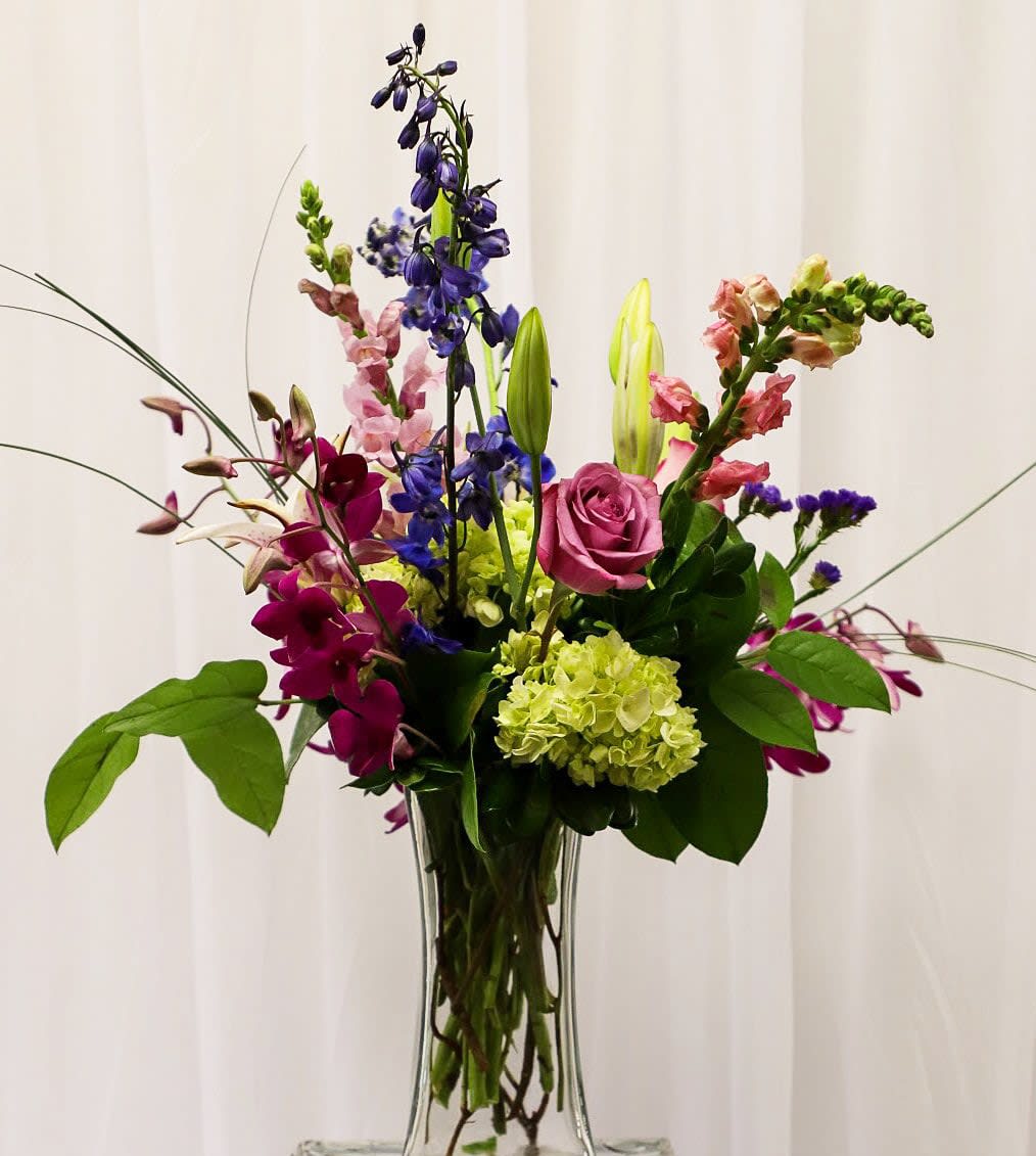 Mixed bouquet in a clear glass vase with pink, purple, and green flowers