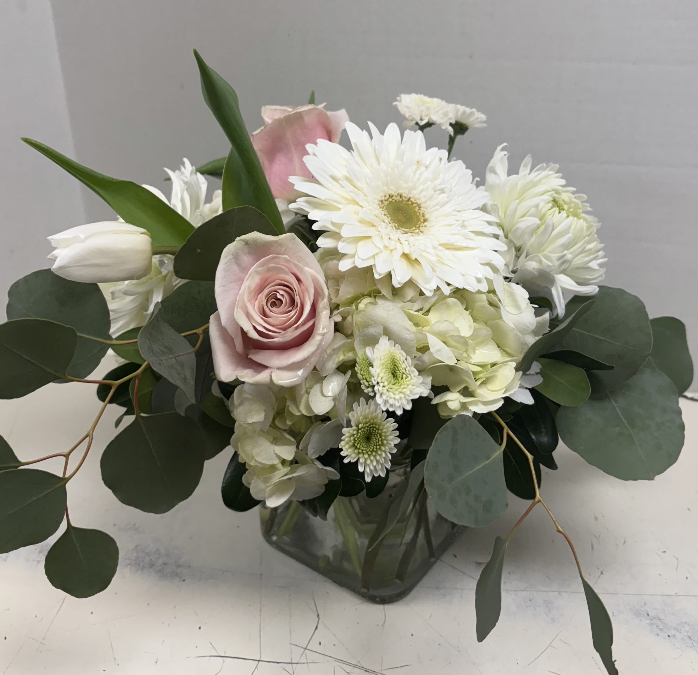 Pink roses and white flowers arranged in a clear glass vase
