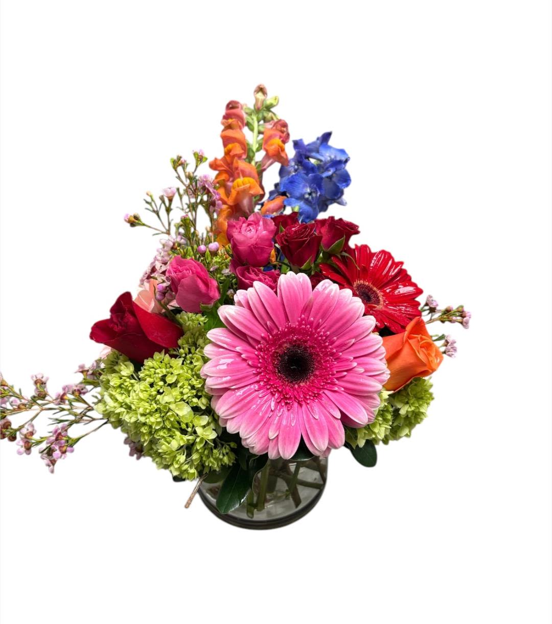 Mixed bouquet with pink gerbera, roses, and blue flowers in a glass vase