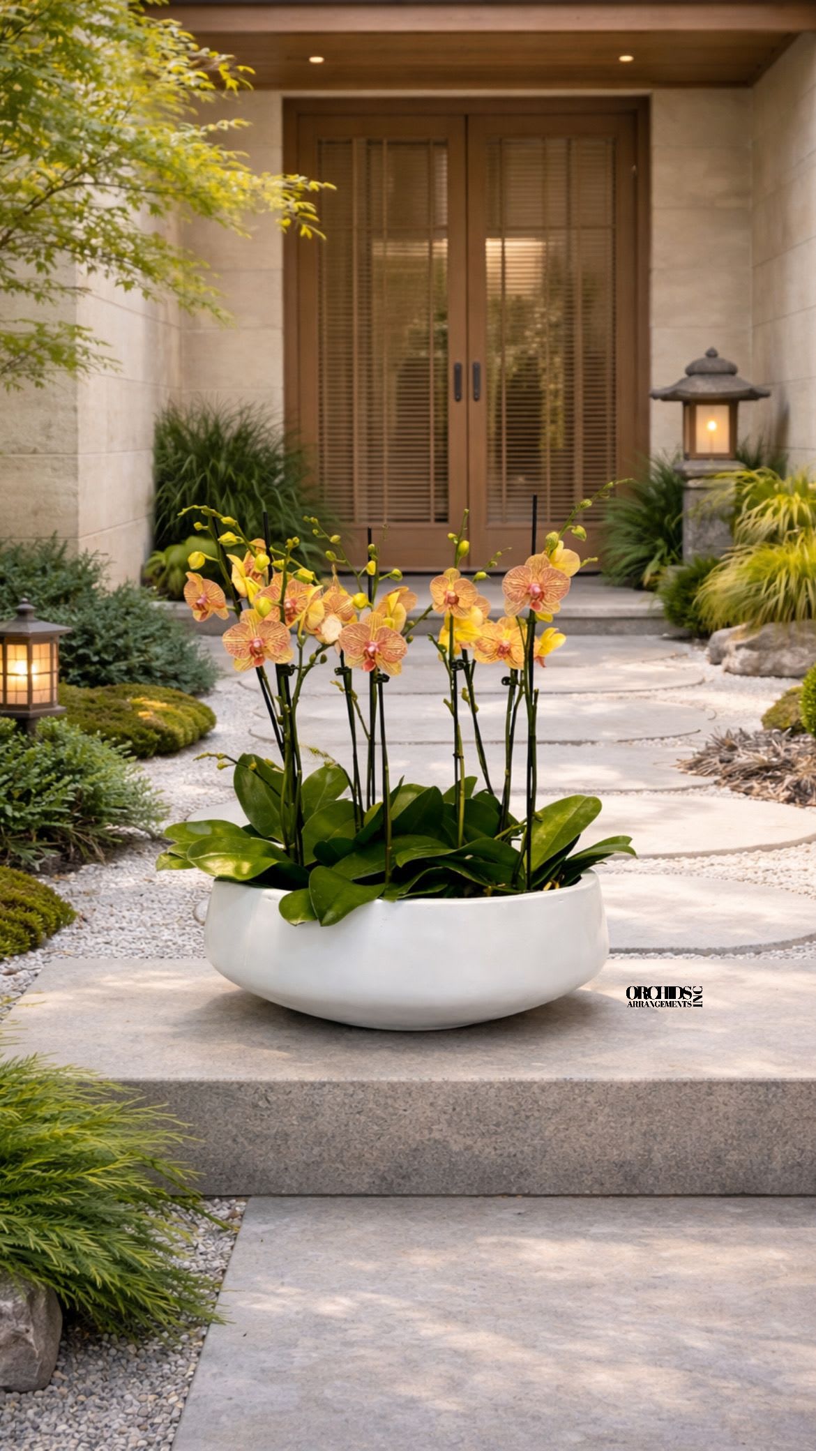 Orchid arrangement in a white bowl planter on a stone walkway
