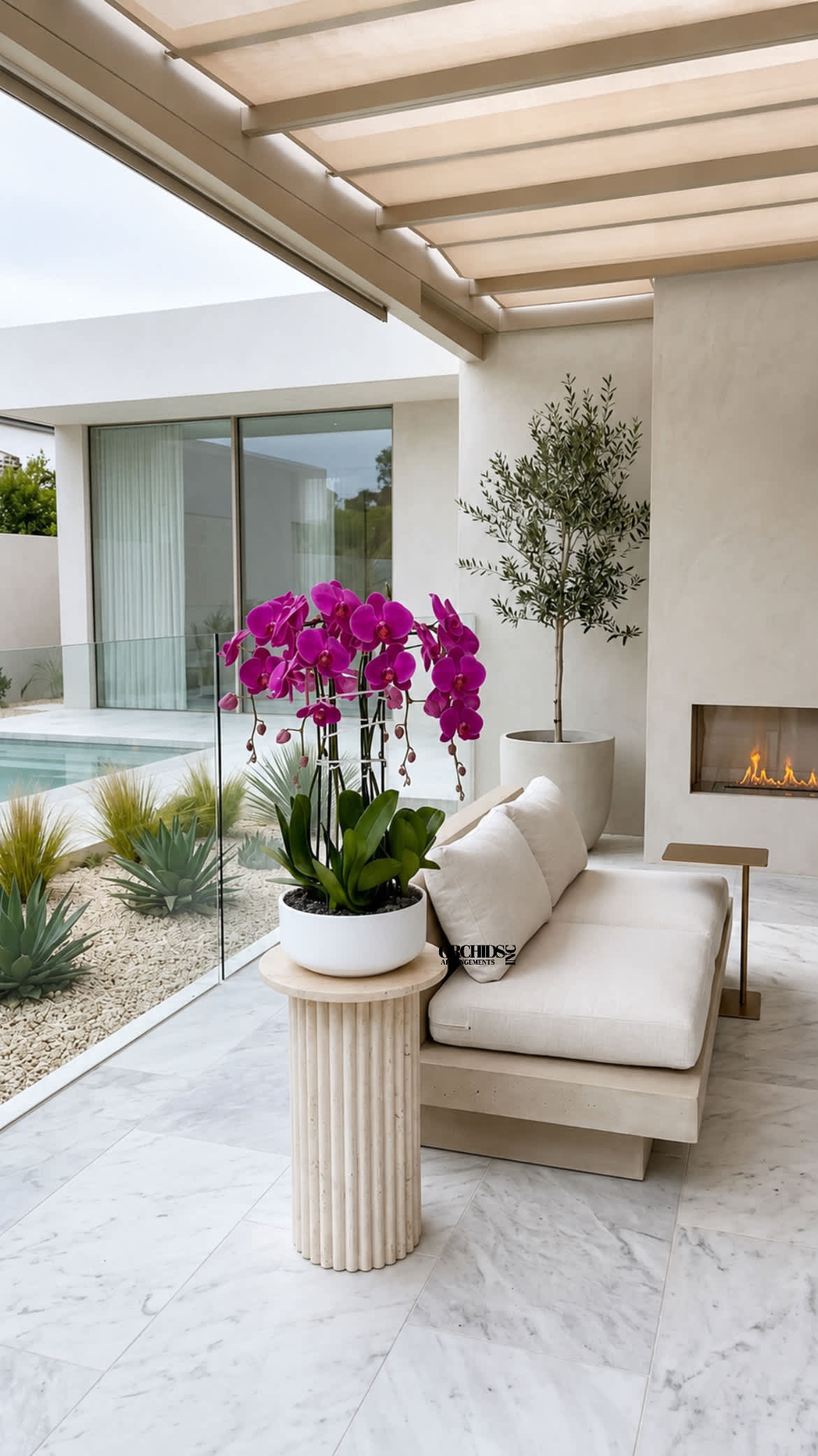 Potted magenta orchids on a small table beside a beige sofa