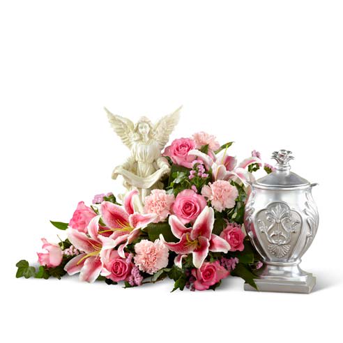 Pink floral arrangement with lilies, roses, and an angel figurine beside a silver urn