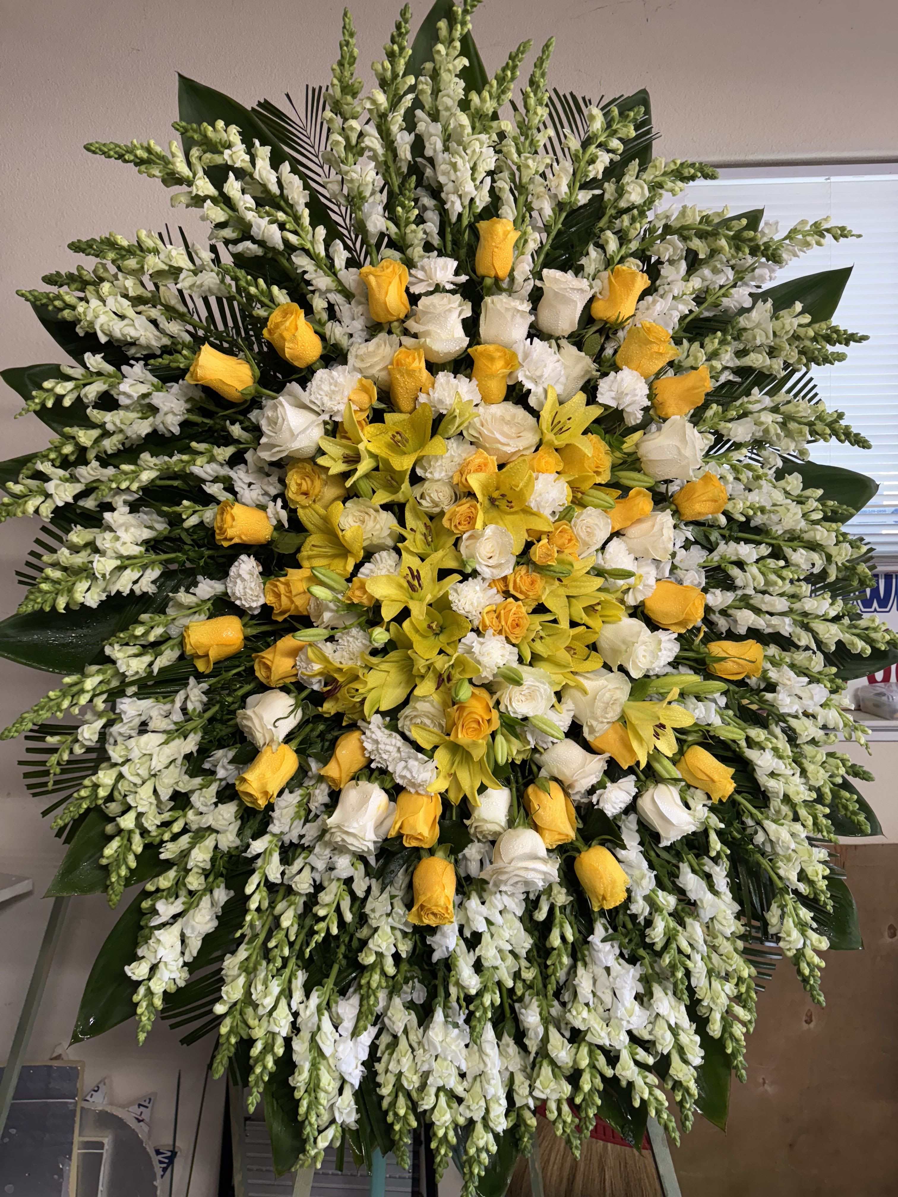 Large yellow and white floral standing spray with roses and lilies