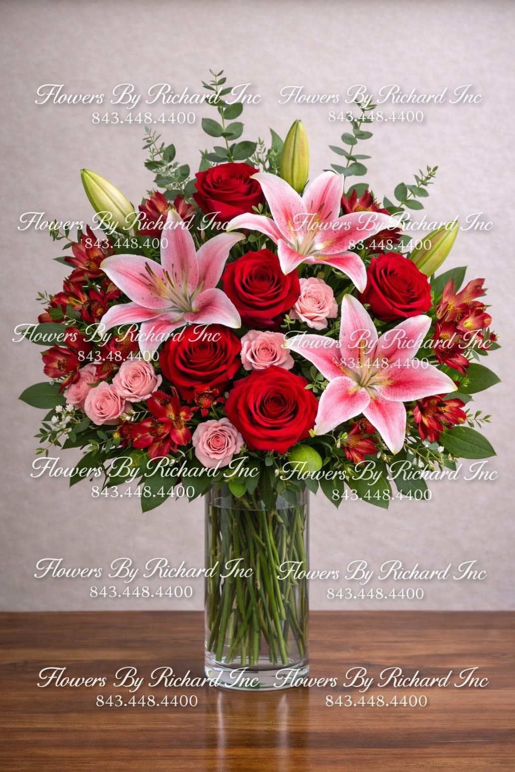 Tall bouquet of red roses and pink lilies in a clear glass vase