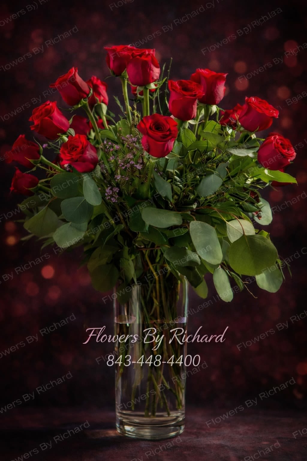 Red roses arranged in a clear glass vase with greenery