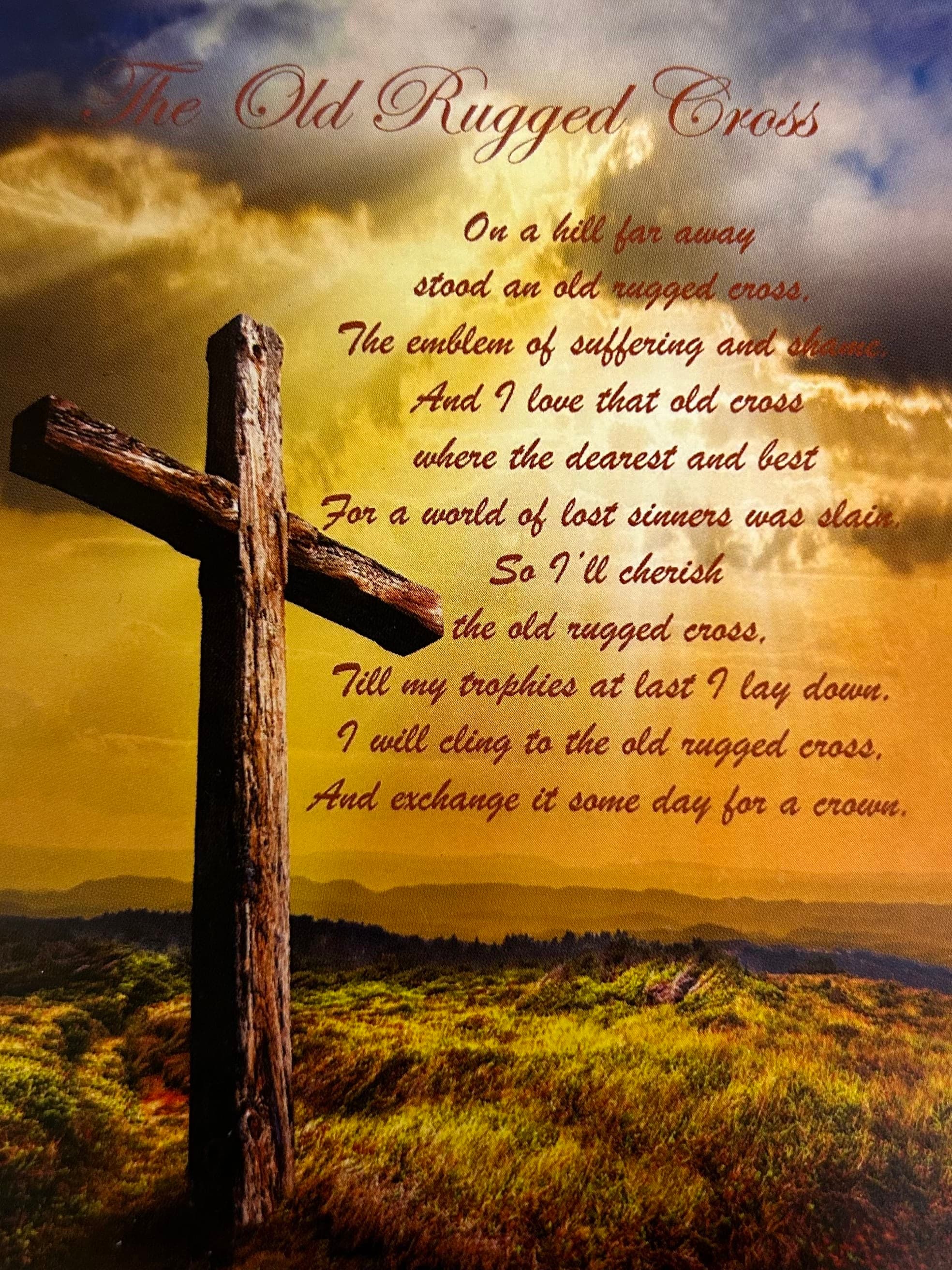 A rustic wooden cross against a golden sky with poem text