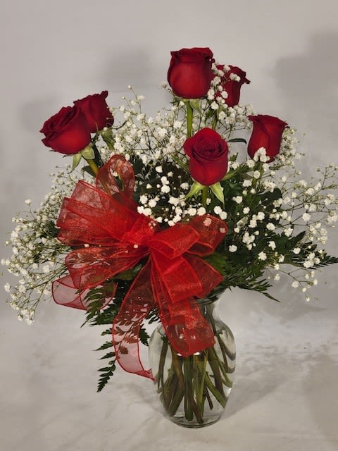 Red roses with baby's breath in a glass vase and red ribbon