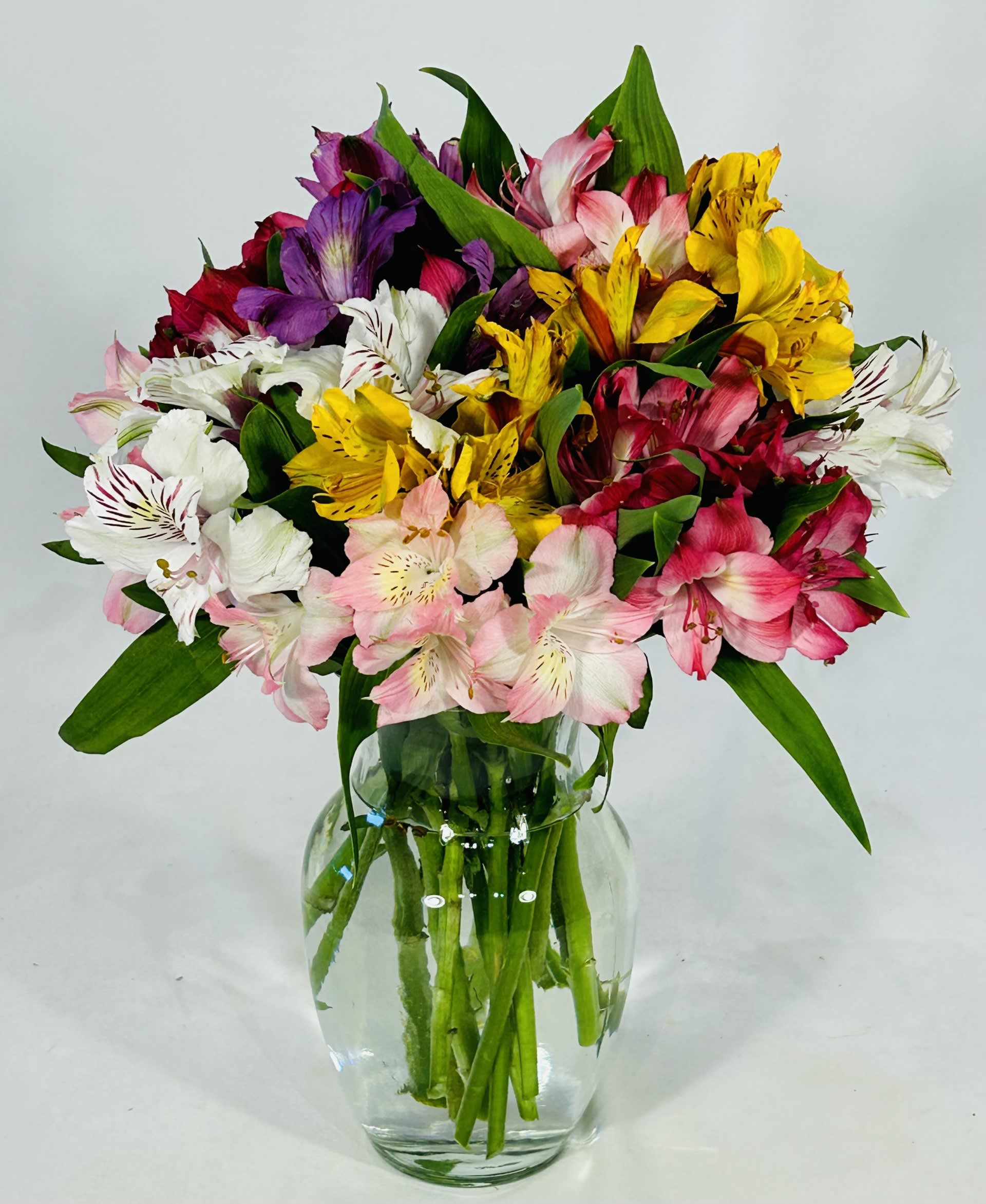 Mixed bouquet of colorful alstroemeria in a clear glass vase
