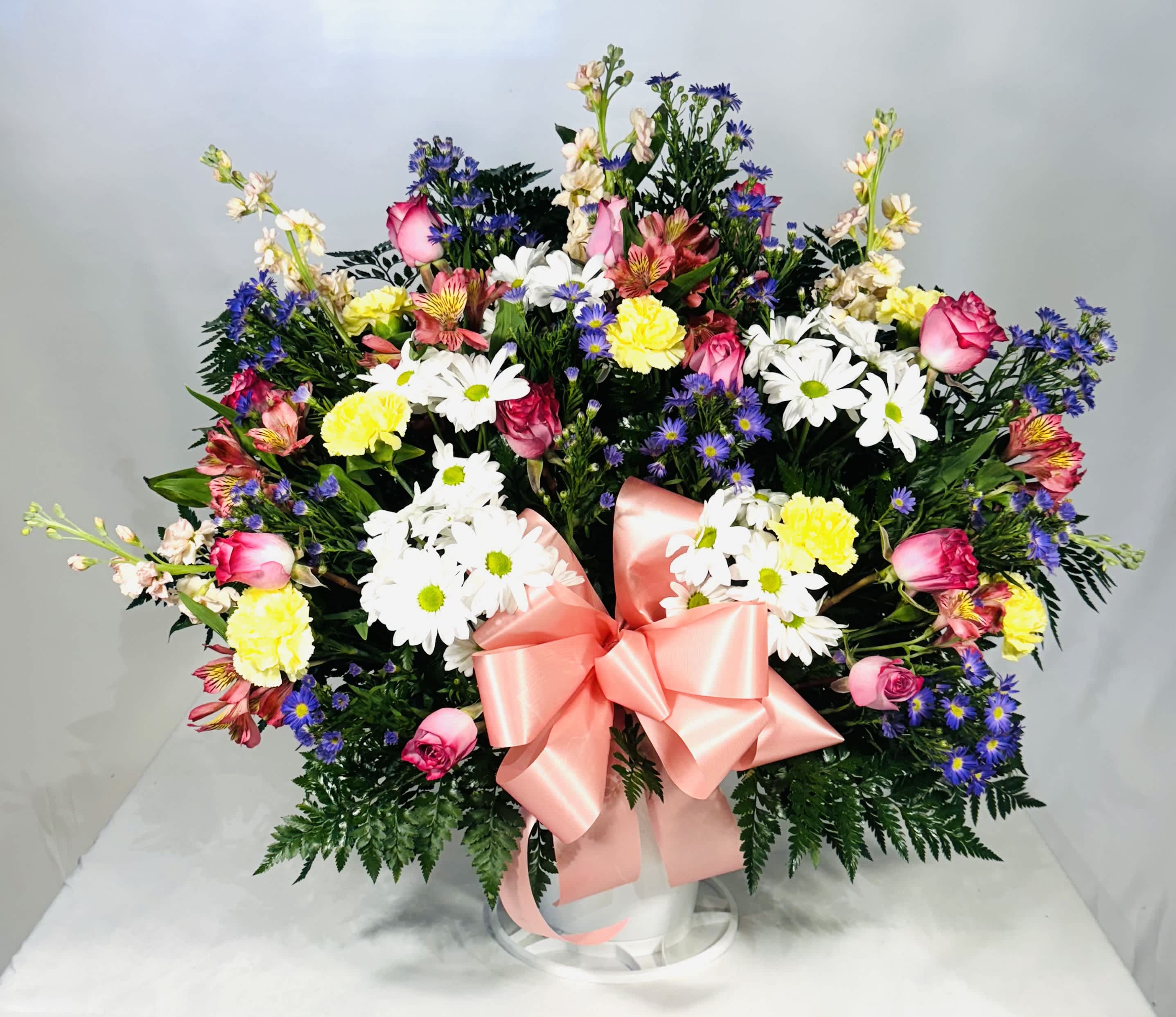 Mixed bouquet of daisies, roses, and carnations with a pink ribbon