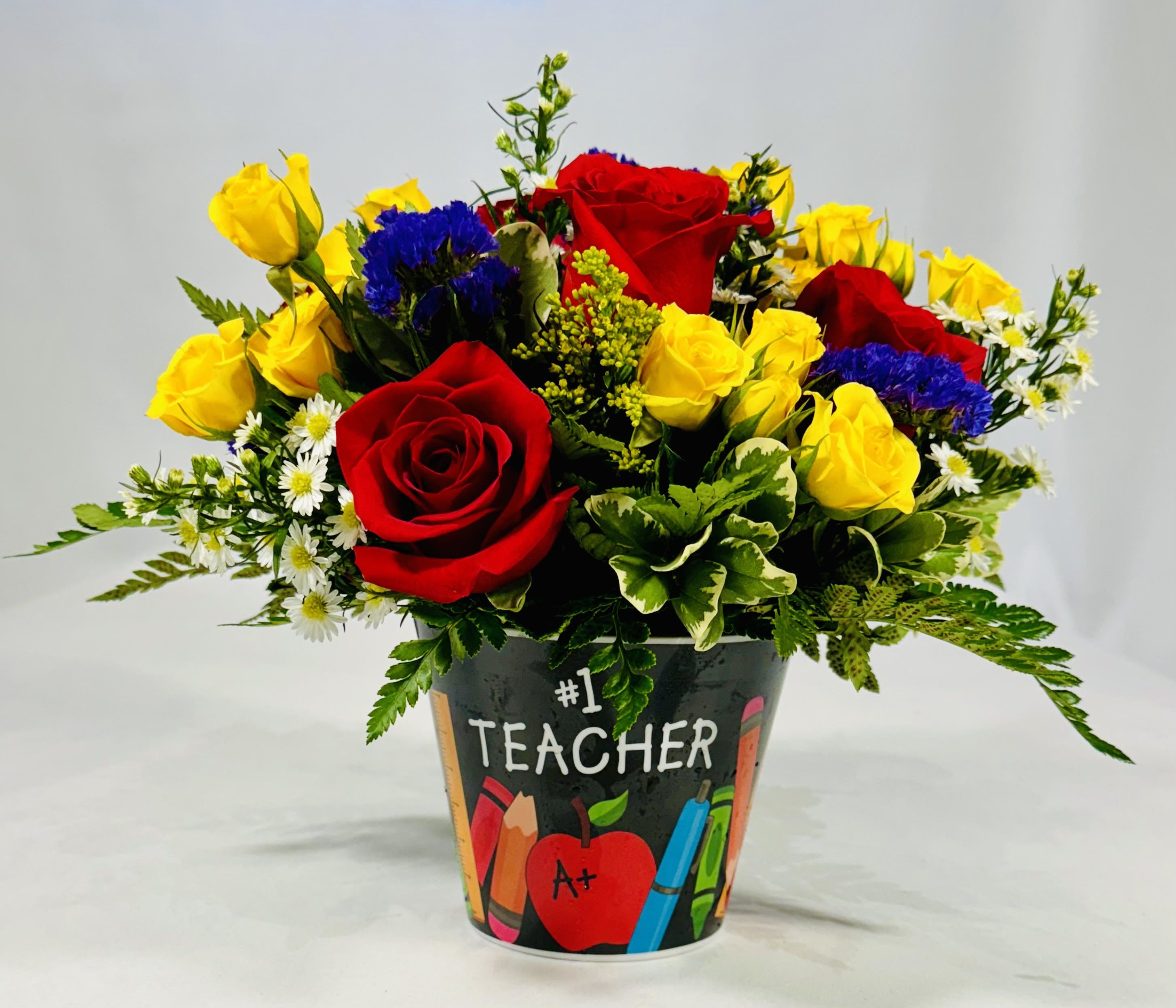Bouquet of red and yellow roses in a teacher-themed container