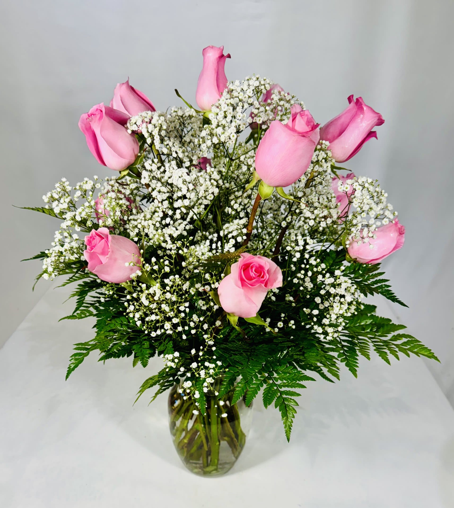 Pink roses arranged with white baby's breath in a glass vase