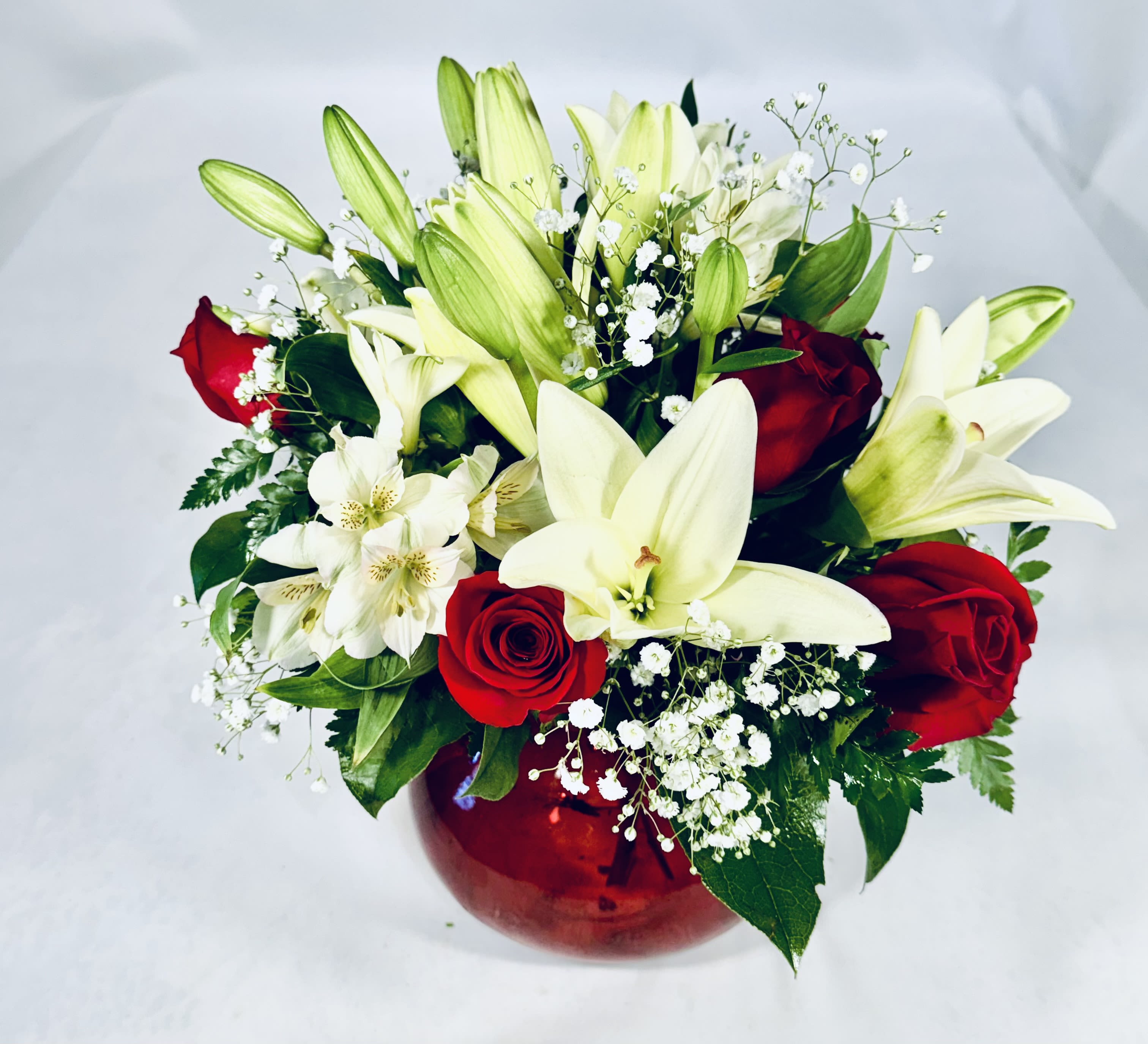 Bouquet of white lilies and red roses in a red glass vase