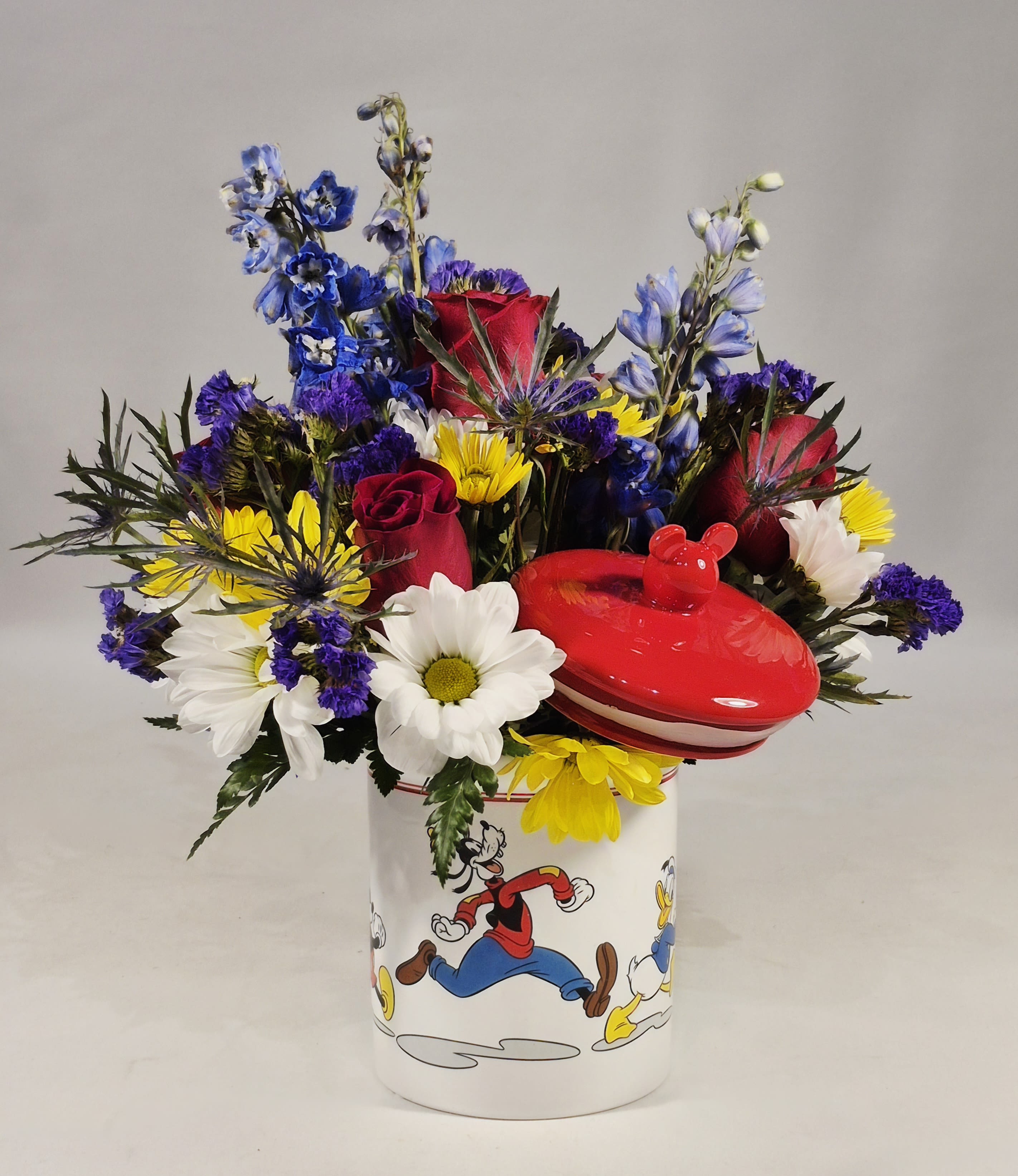 Mixed bouquet in a Disney-themed mug with a red lidded container