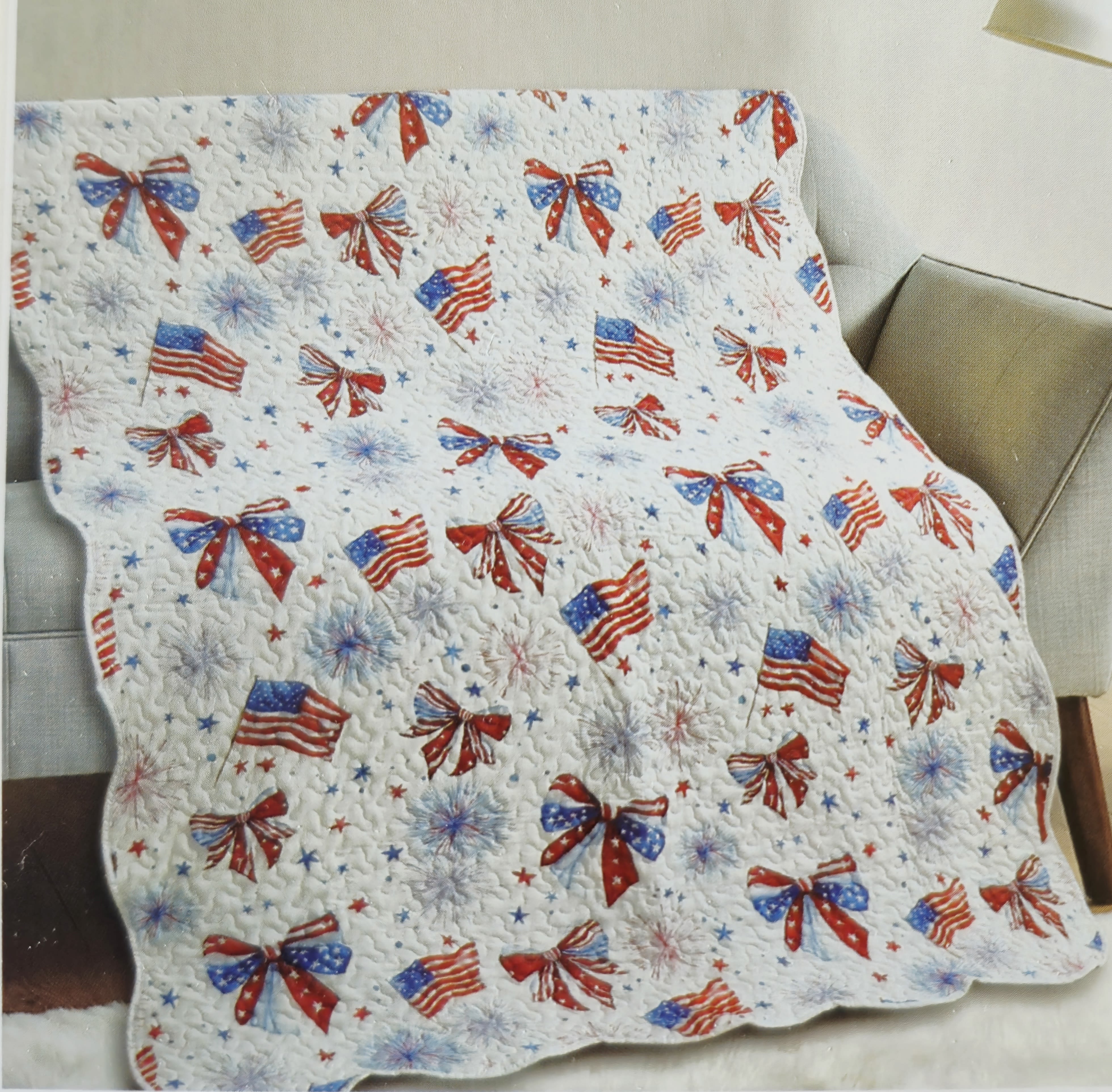 Patriotic Red, White and Blue Throw - A cheerful quilted throw patterned with red, white and blue bows, flags and starbursts that brings instant Fourth of July charm to any living room or porch - perfect as a casual patriotic gift or a festive home décor accent for Memorial Day, Independence Day, or veterans' celebrations. The throw reads like a warm, handmade accent that will make the person you're thinking of feel seen and celebrated with its lively Americana motif.  Made from a soft, stitched quilted fabric with a white background and repeating red, white and blue motifs, this 50 x 60-inch throw has a cozy weight suited for draping over a sofa, chair, or picnic bench. The stitched texture gives it a tactile, handcrafted look that layers beautifully with neutral or navy furnishings; pictured with modern black metal plant stand and seating to suggest easy styling in indoor or covered outdoor spaces.  Give it as a thoughtful seasonal gift - for grandparents, hosts of a backyard barbecue, or anyone who loves classic Americana style - and know it's sized for everyday use and cuddling. Simple care: machine wash gentle to preserve the quilted texture and bright colors so it stays festive for many holidays to come.