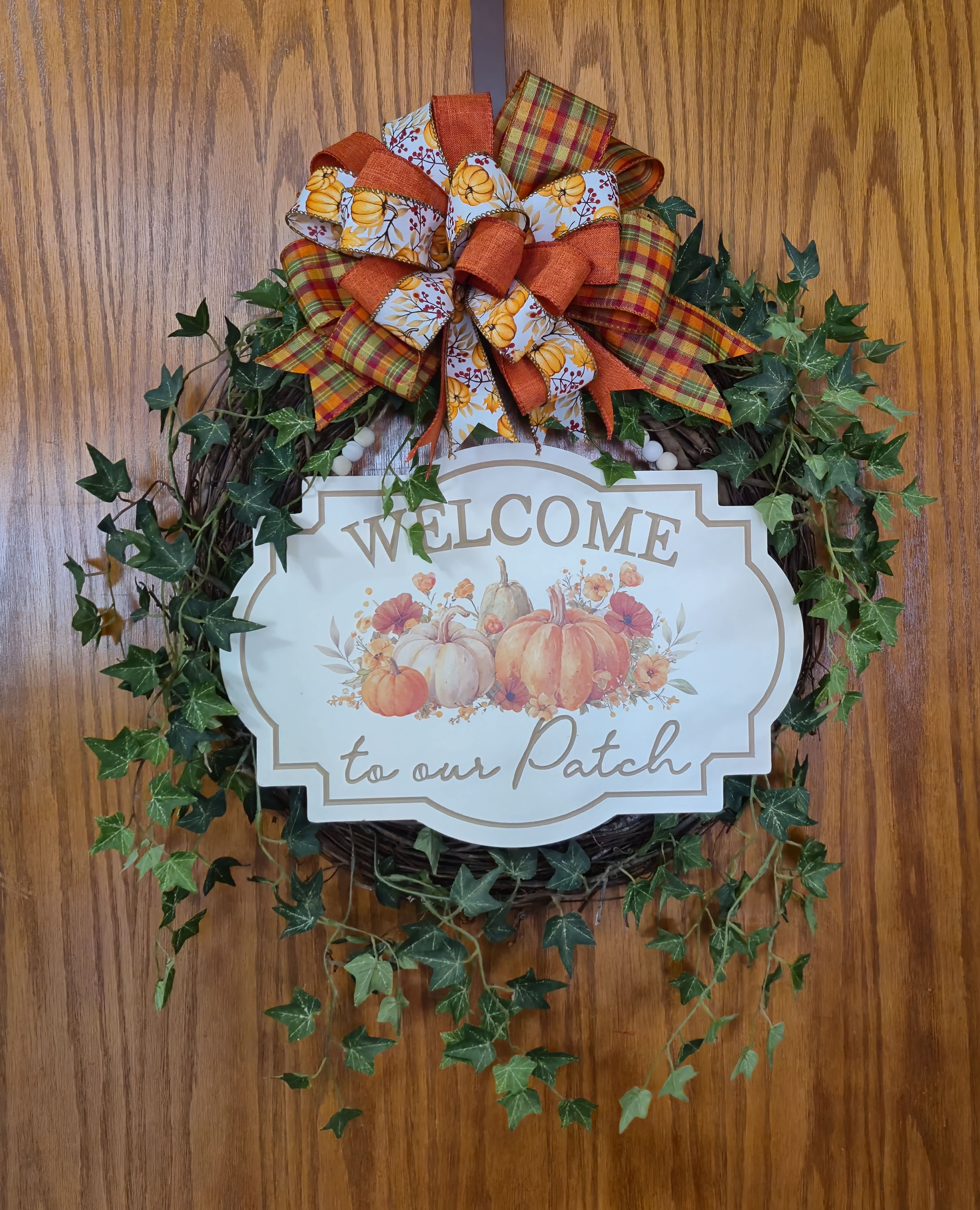 Fall wreath with a pumpkin welcome sign and plaid bow