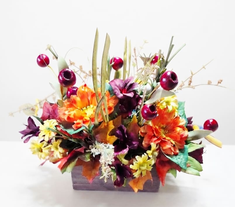 Colorful floral arrangement in a rectangular container with orange, purple, and yellow blooms