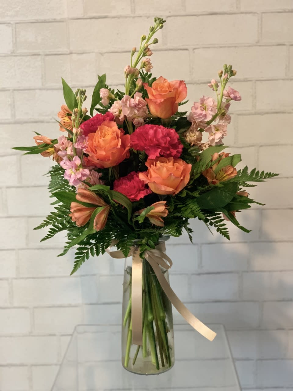 Bouquet of orange roses and pink carnations in a glass vase