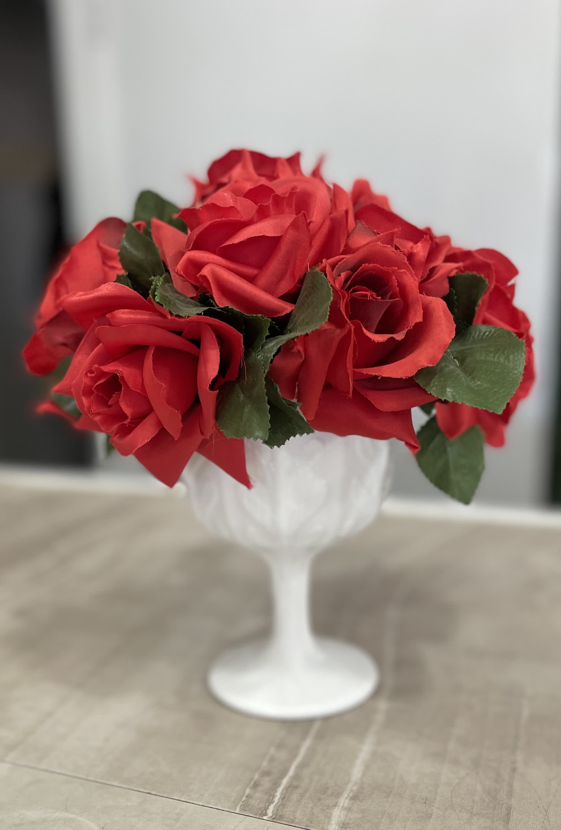 Red roses arranged in a white goblet vase