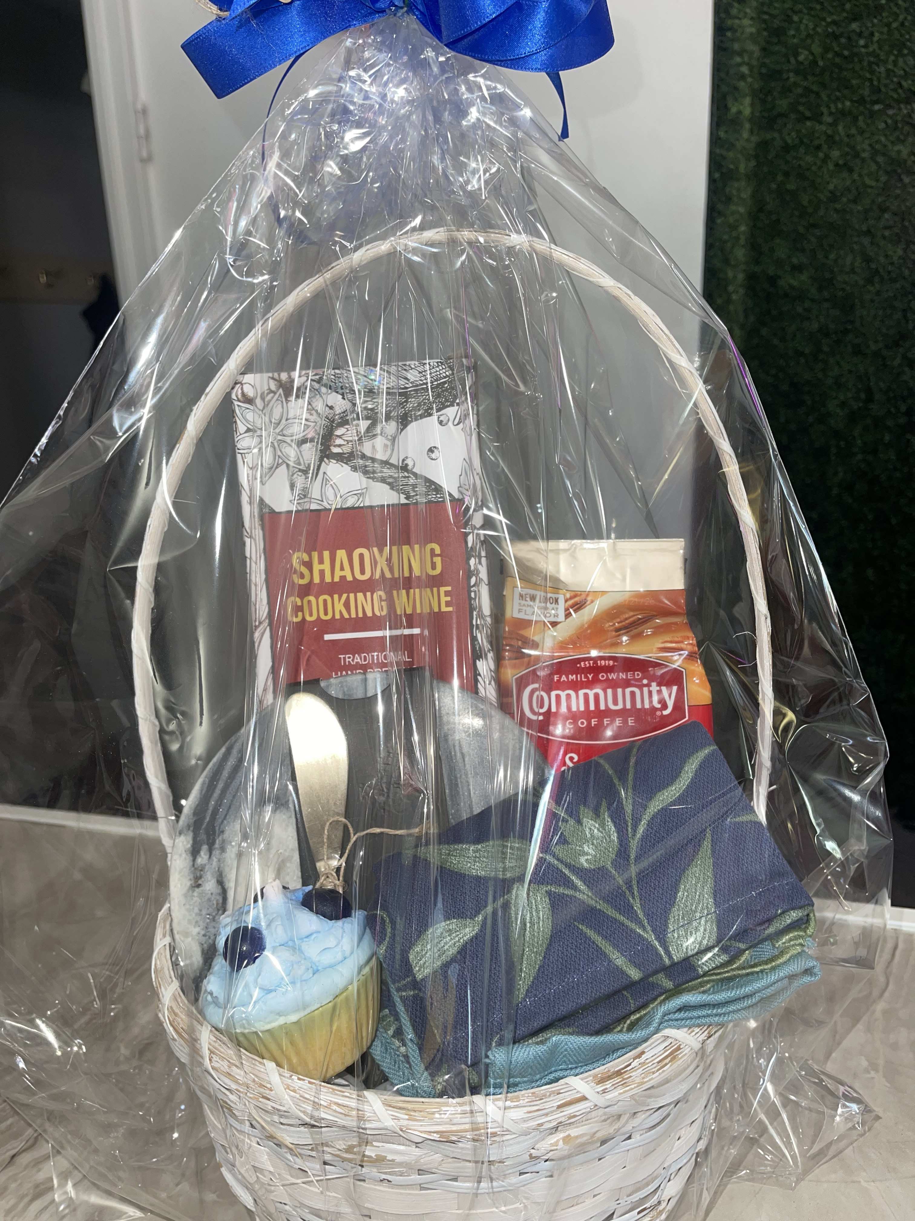 Gift basket with cooking wine, coffee, folded napkins, and a cupcake
