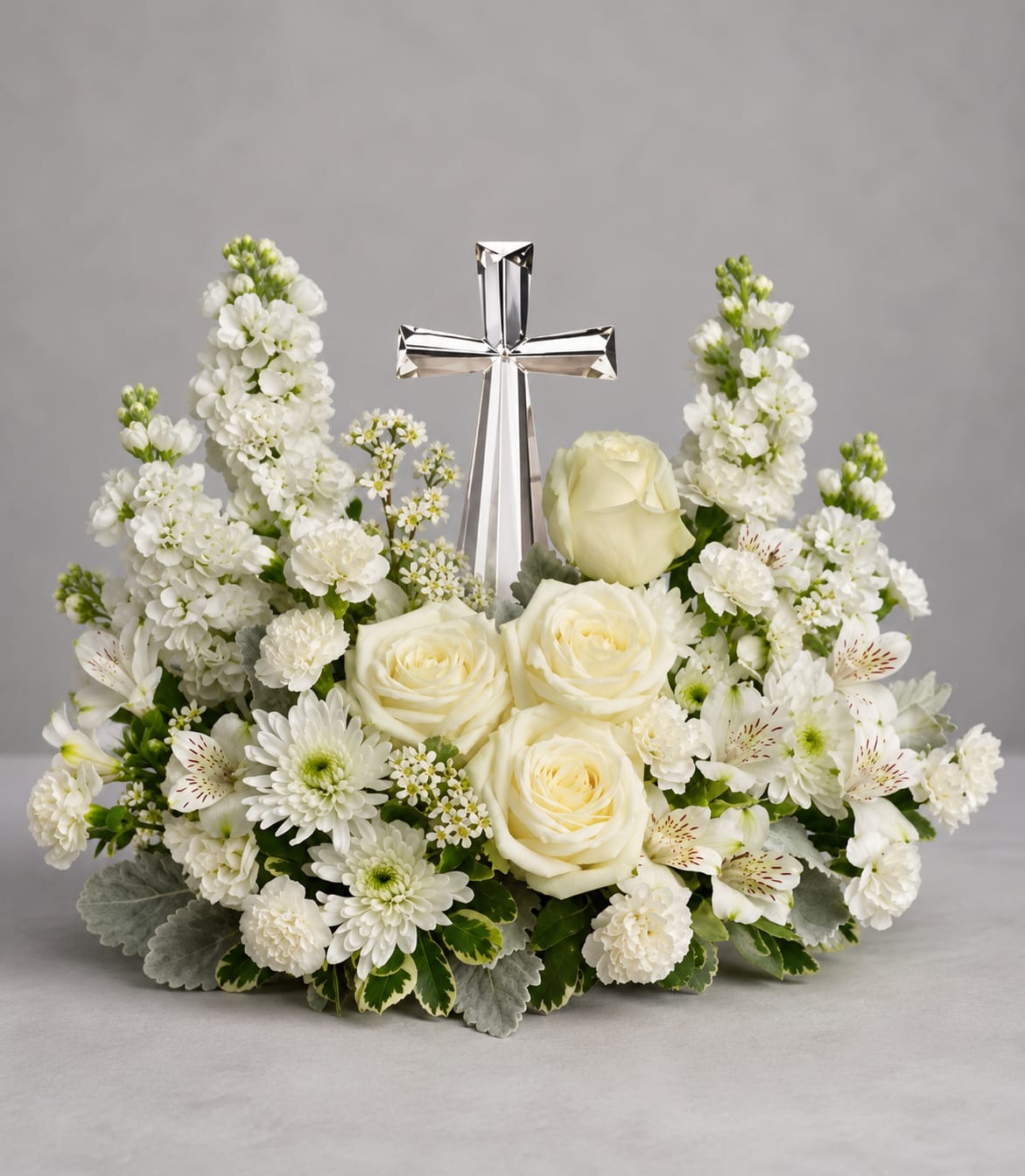 Divine Peace Cross - An elegant display of faith and divine peace, this beautiful arrangement will comfort the bereaved in a truly thoughtful and respectful way. An exquisite crystal cross is surrounded by a bed of lovely blossoms. It is sure to be appreciated and always remembered. A fragrant mix of pure white blooms - including roses, alstroemeria, stock, carnations and waxflower - is accented with dusty miller and variegated pittosporum around an exclusive Crystal Cross keepsake. Orientation: One-Sided 