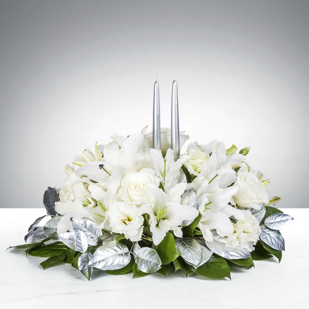 White floral centerpiece with two silver taper candles