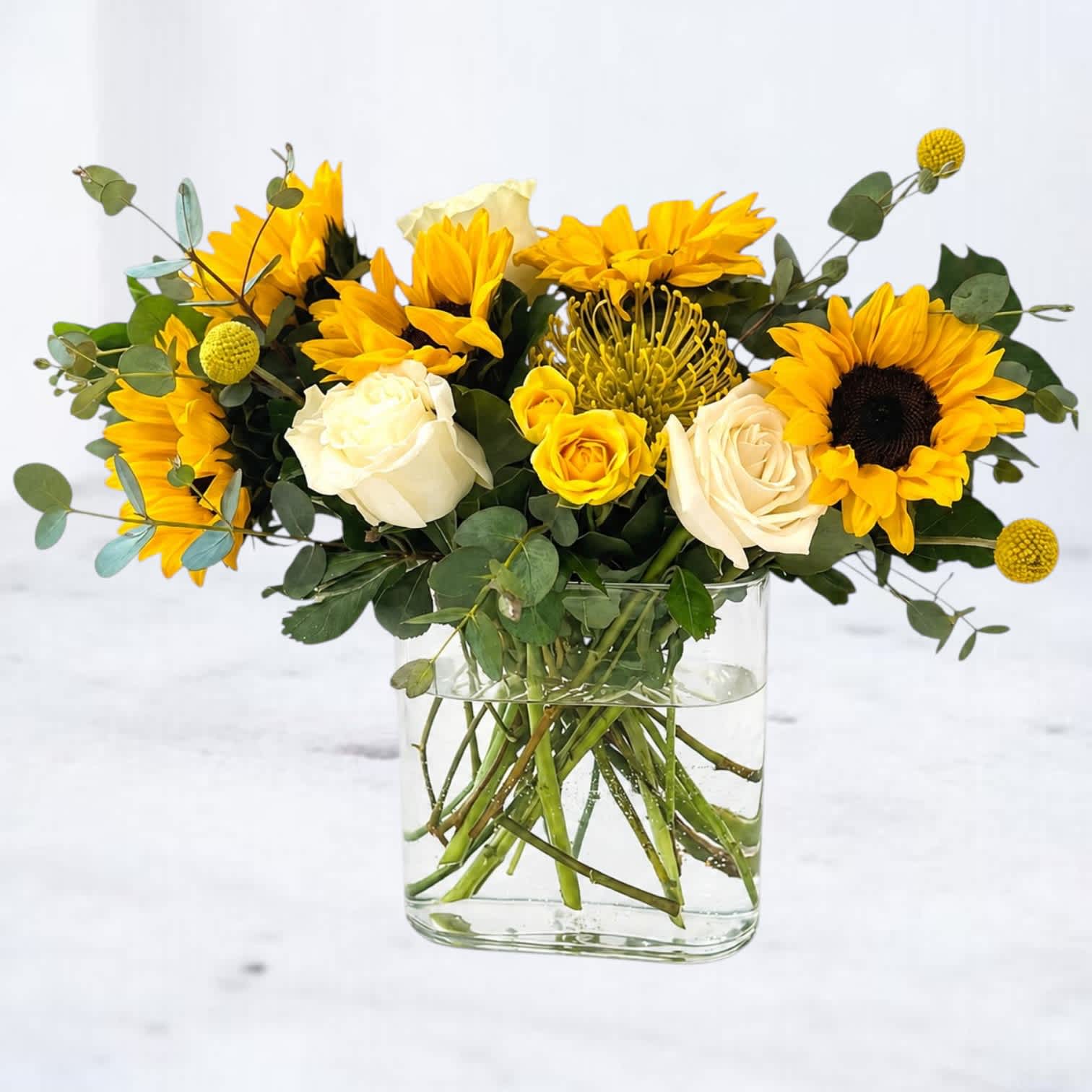 Yellow sunflowers and white roses arranged in a clear glass vase