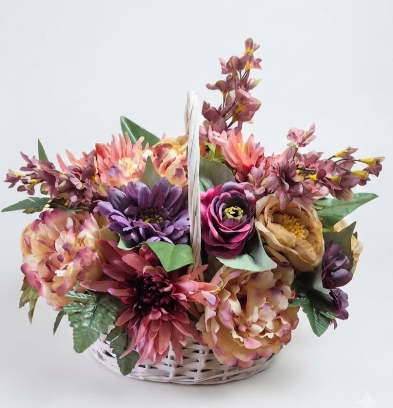 Basket arrangement of multicolored flowers in pink, purple, and peach tones