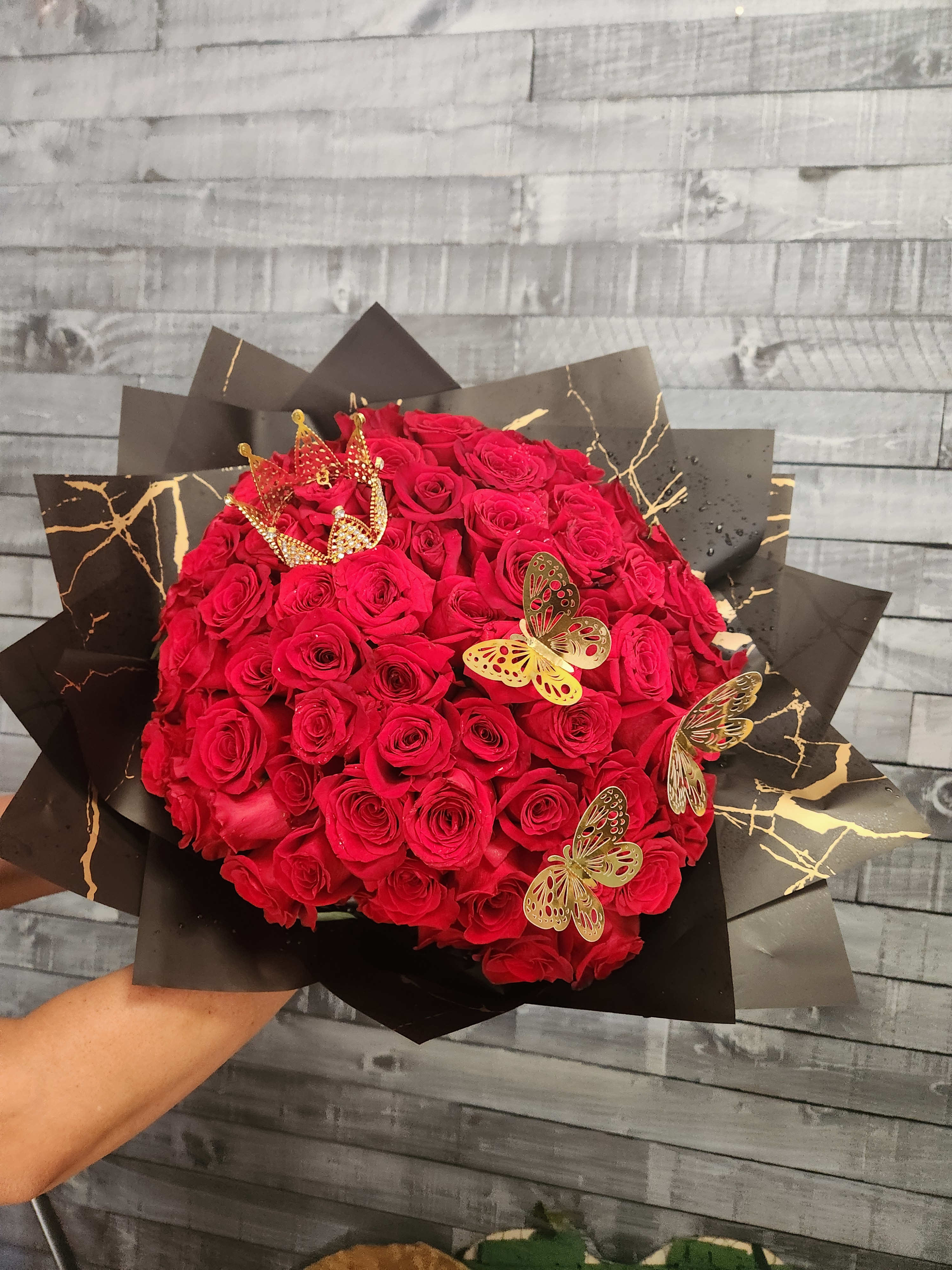 Large bouquet of red roses wrapped in black paper with gold accents