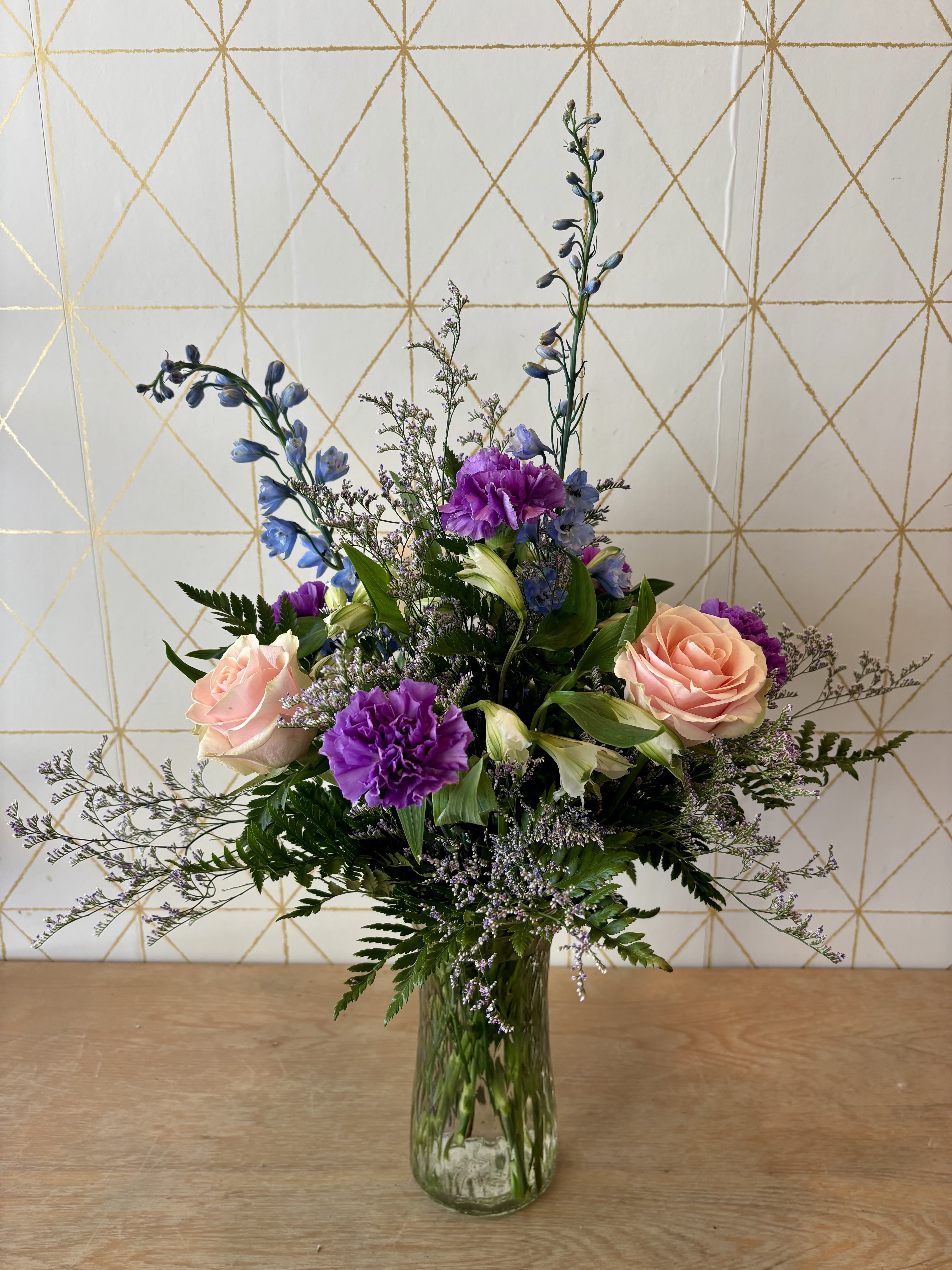 Mixed bouquet of pink roses and purple flowers in a glass vase