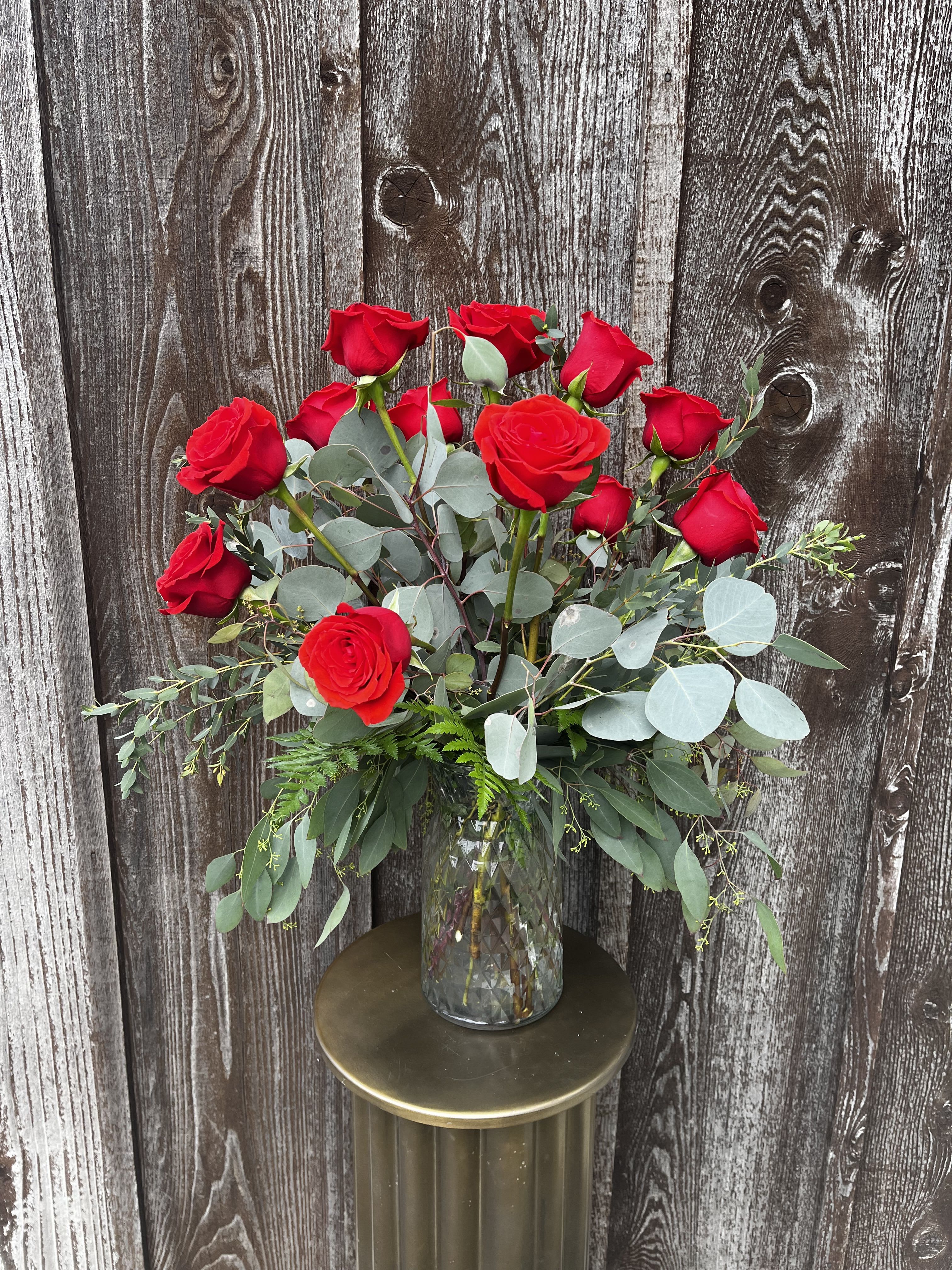 Red roses in a clear glass vase with eucalyptus