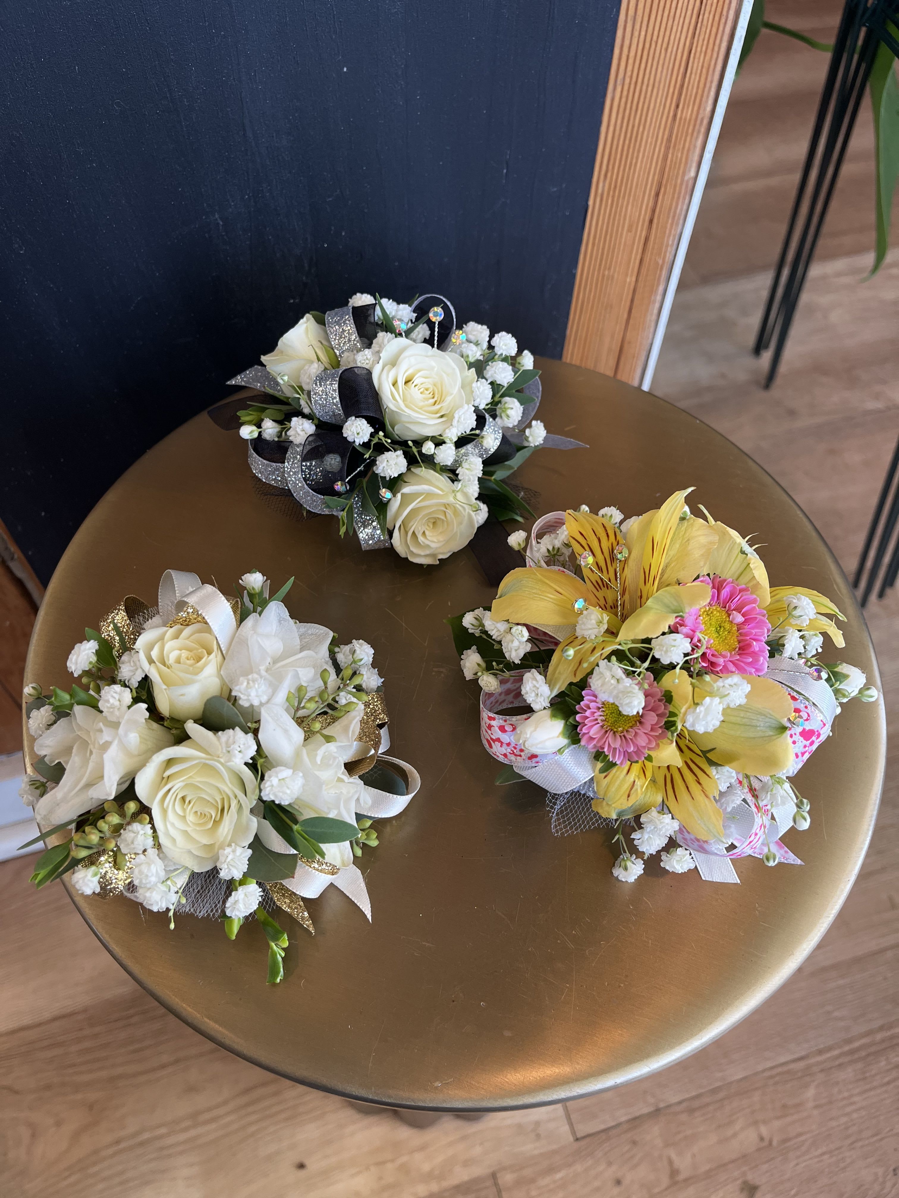 Three small floral bouquets with white roses and yellow blooms on a round table.
