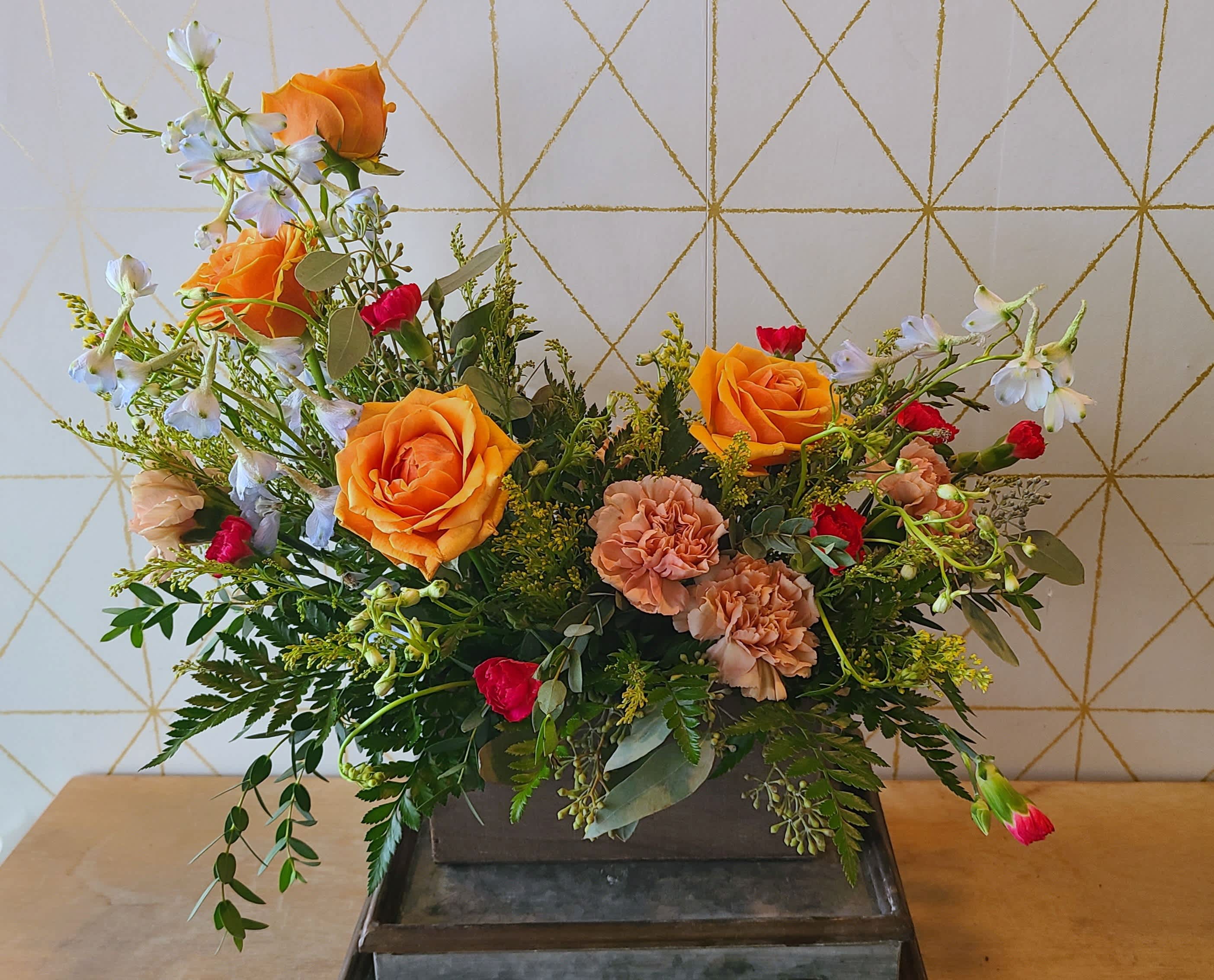 Mixed bouquet with orange roses, peach carnations, and white blossoms in a rectangular container