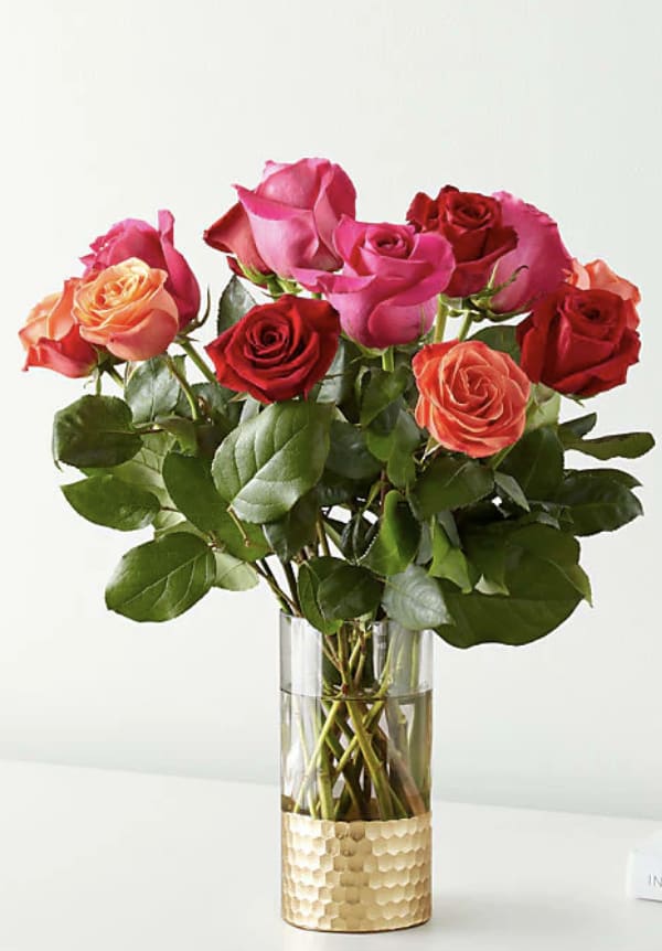 Bouquet of pink, red, and peach roses in a clear glass vase