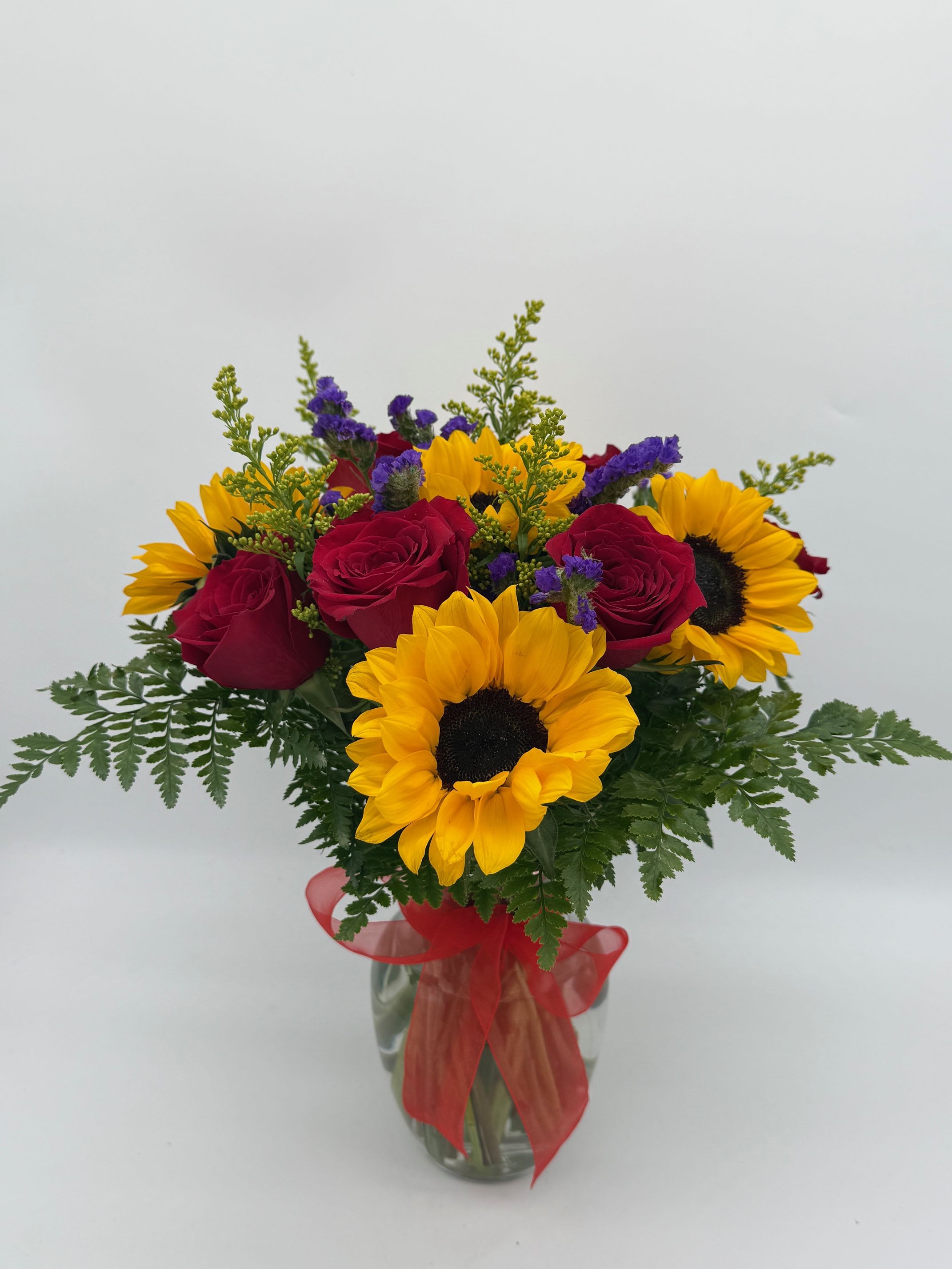Bouquet of red roses and yellow sunflowers in a glass vase