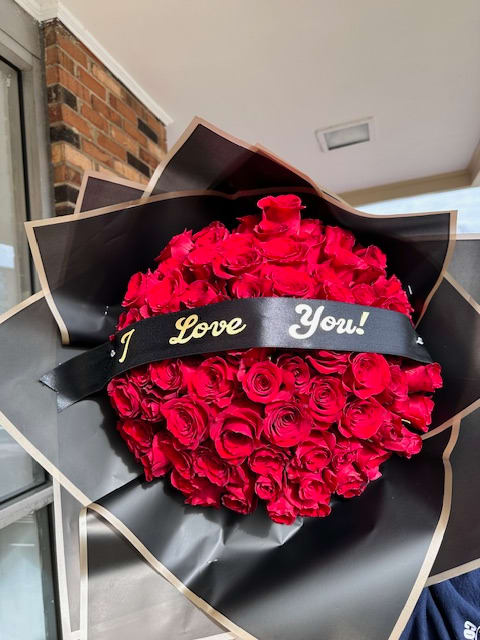 Large bouquet of red roses wrapped in black paper with a "I Love You!" ribbon