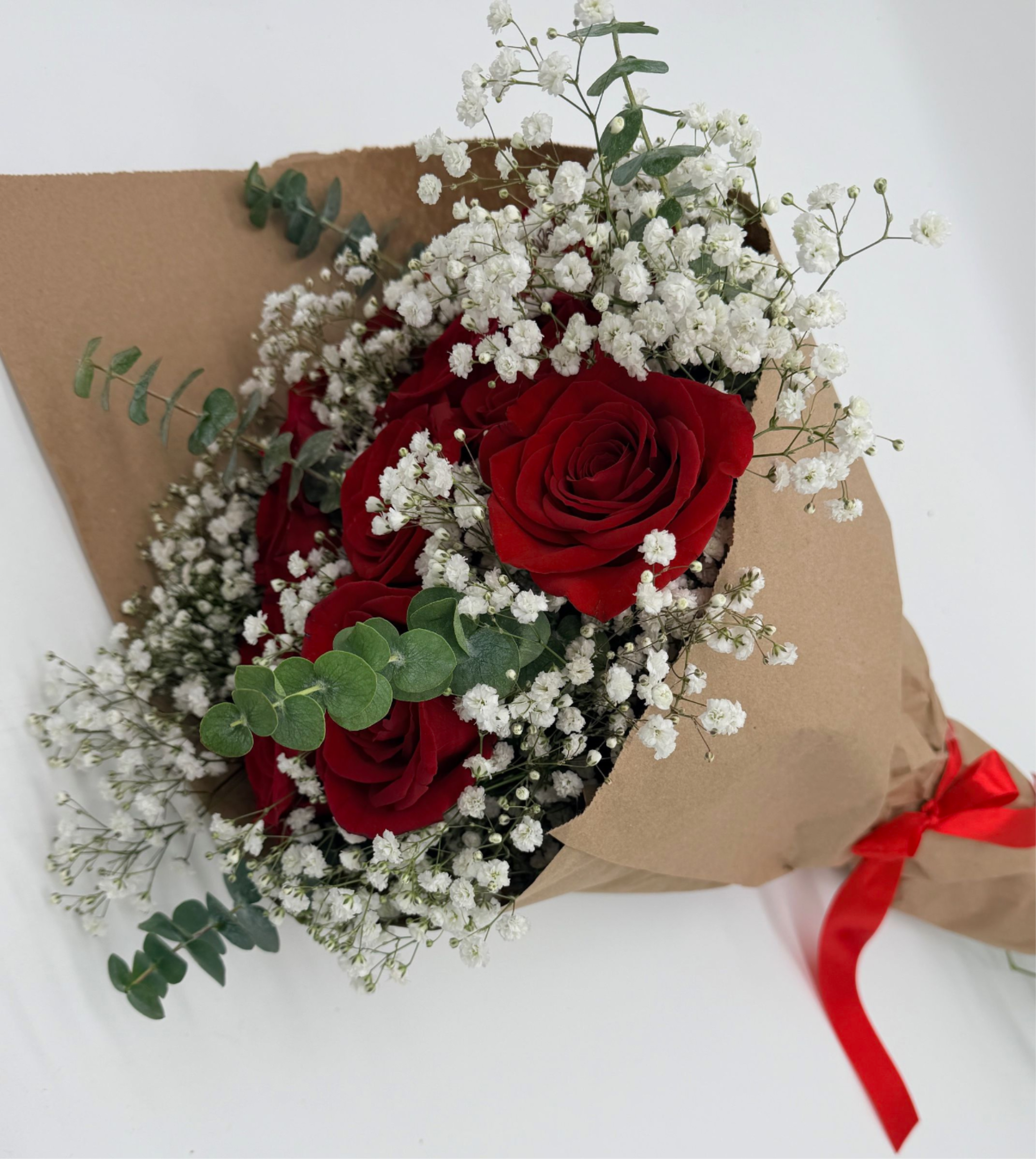 Bouquet of red roses and white baby's breath wrapped in brown paper