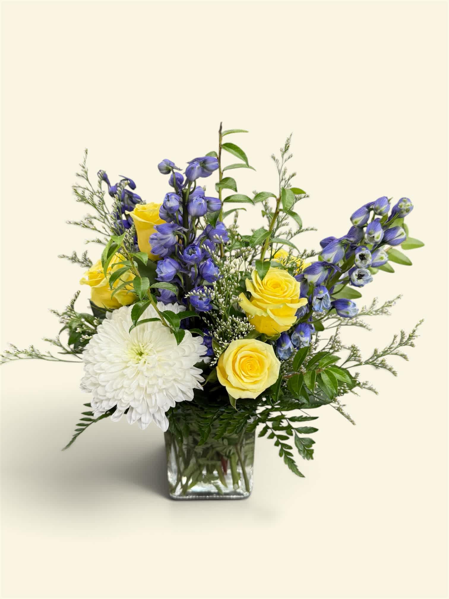 Yellow roses and white chrysanthemum in a glass vase with blue flowers