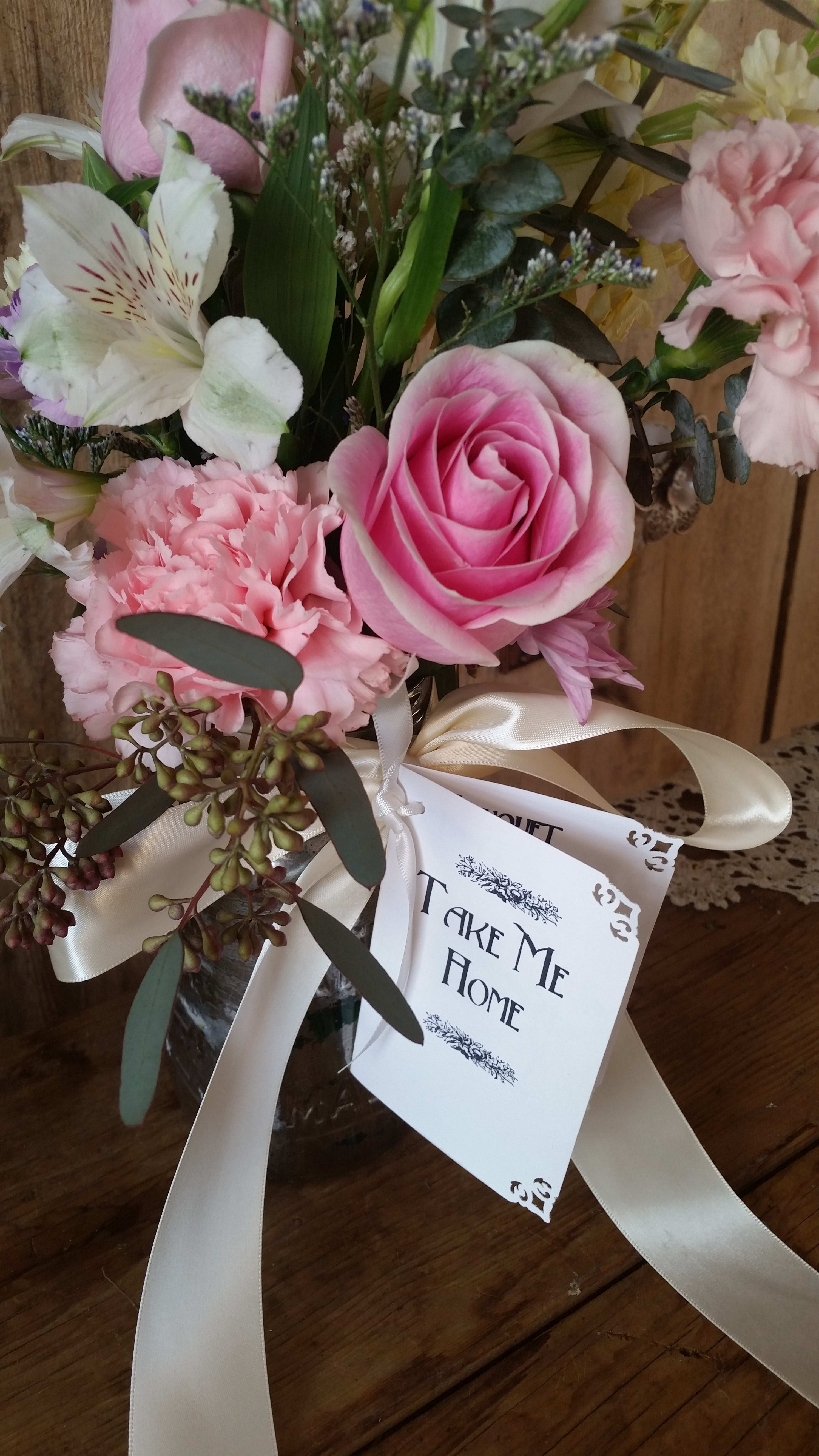 Pink rose and carnations in a glass vase with a ribbon and gift tag