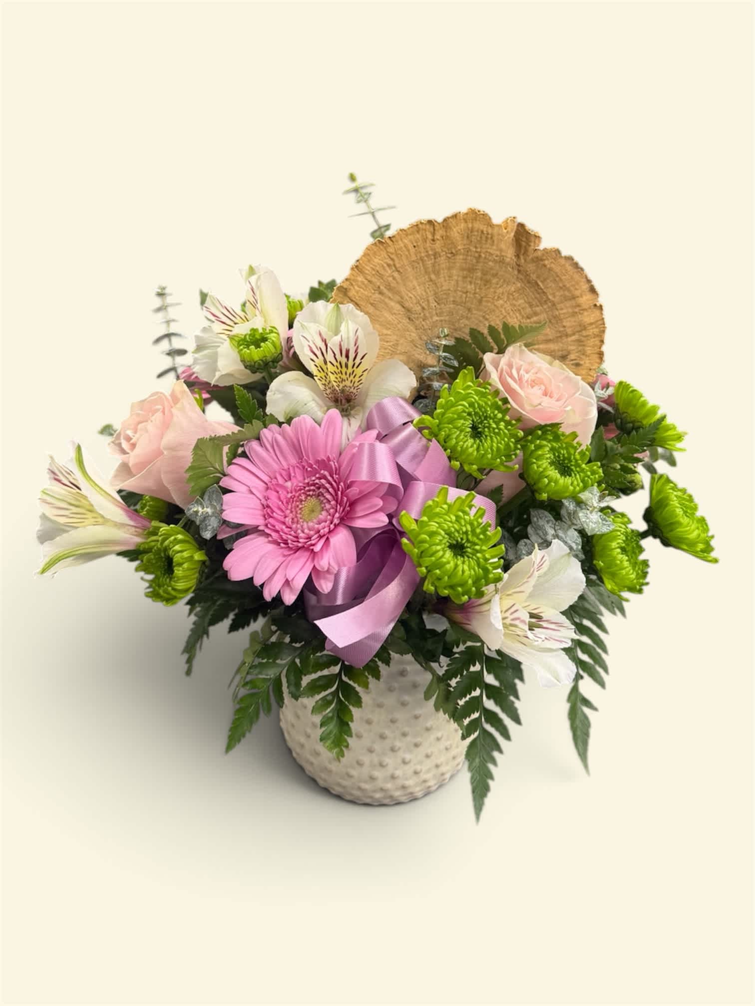 Pink gerbera and pale roses in a white textured vase with a ribbon