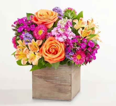 Mixed bouquet of orange roses and colorful flowers in a wooden box