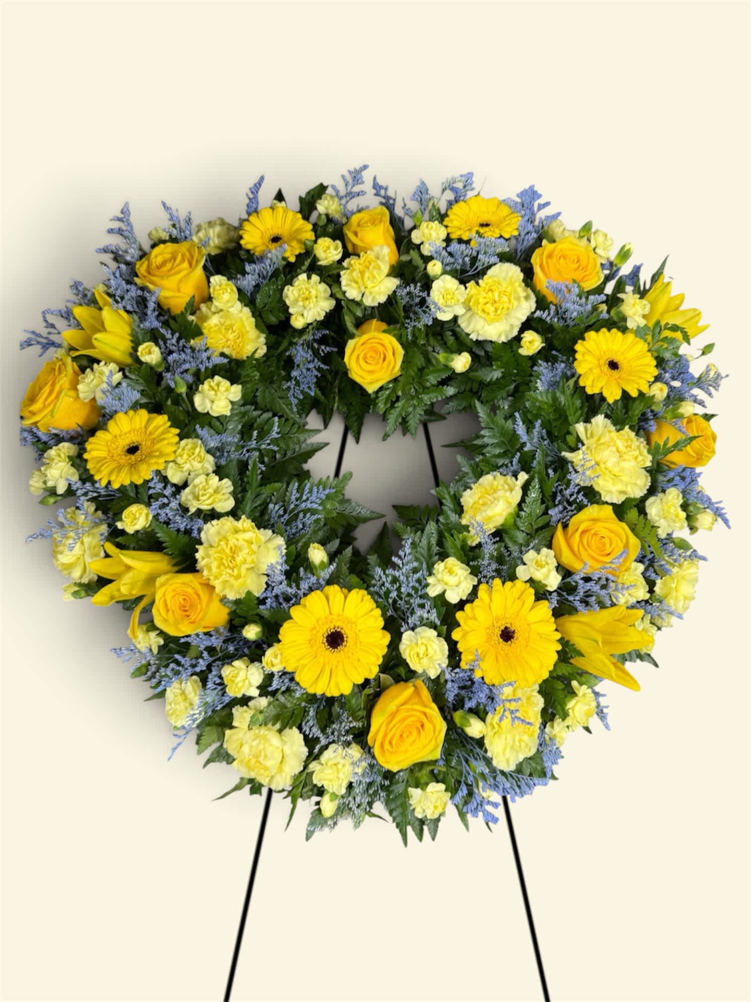 Heart-shaped floral wreath with yellow roses and daisies on a stand
