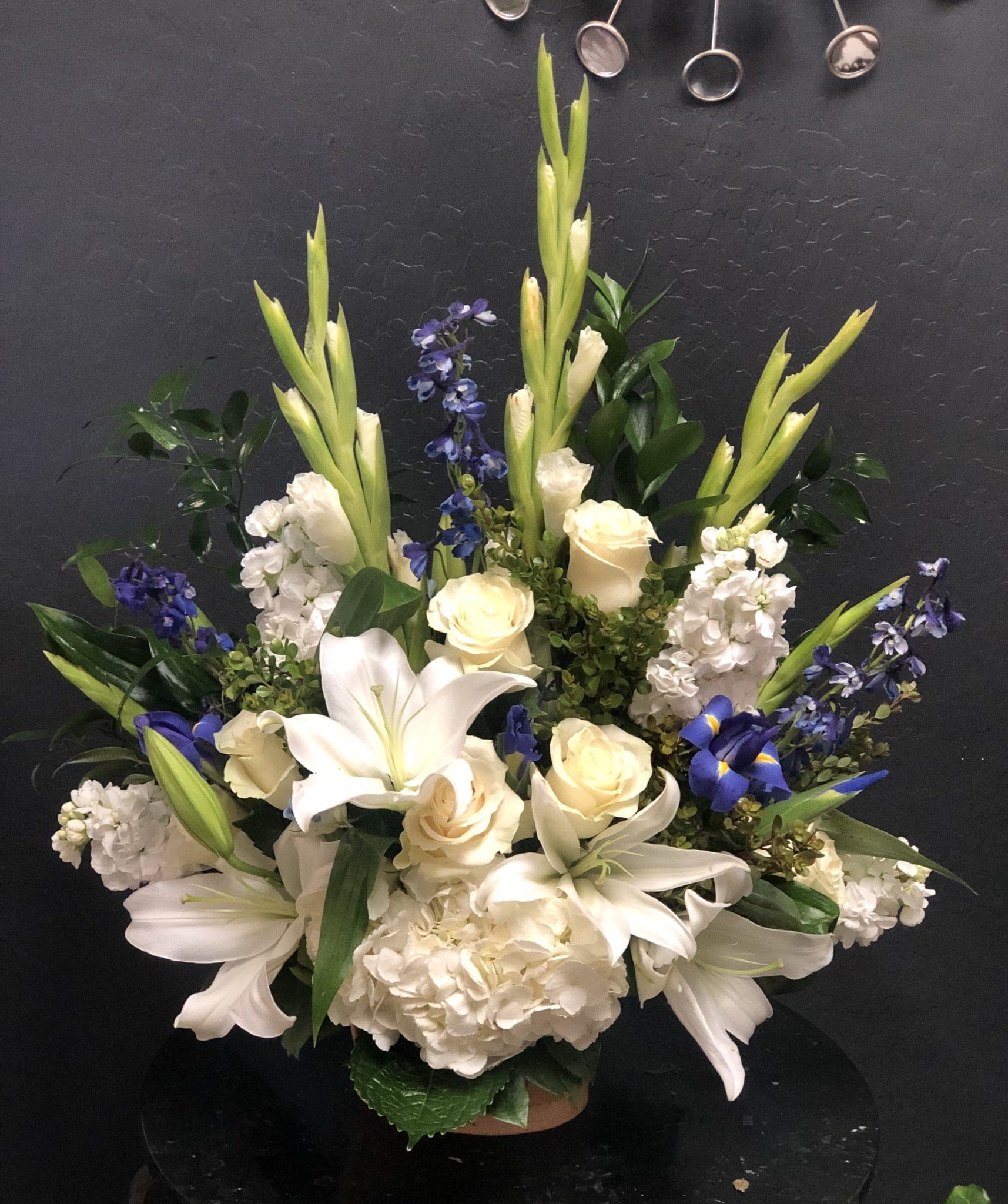 White lilies, cream roses, and blue flowers arranged in a vase