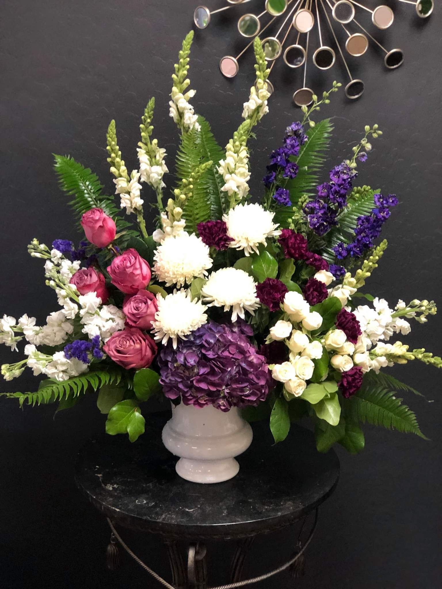 Large mixed floral arrangement in a white pedestal vase