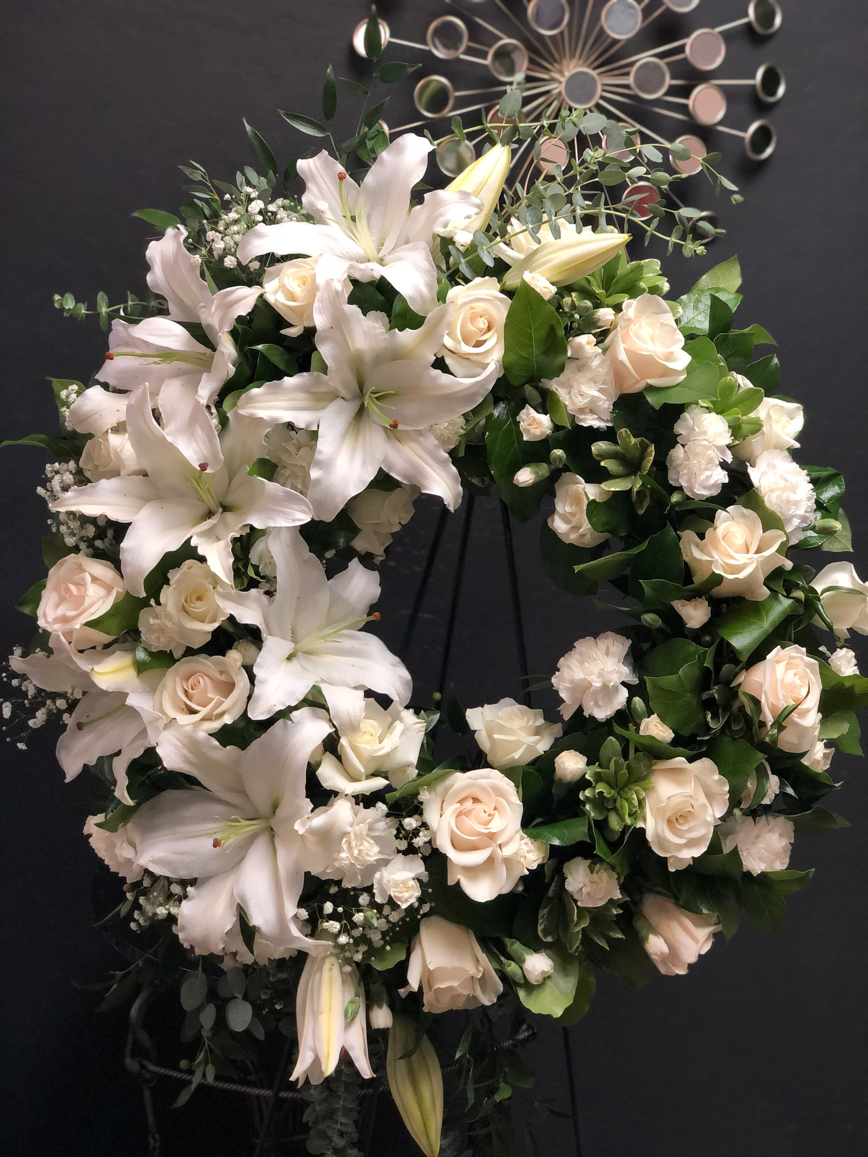 White lily and rose wreath on a dark stand
