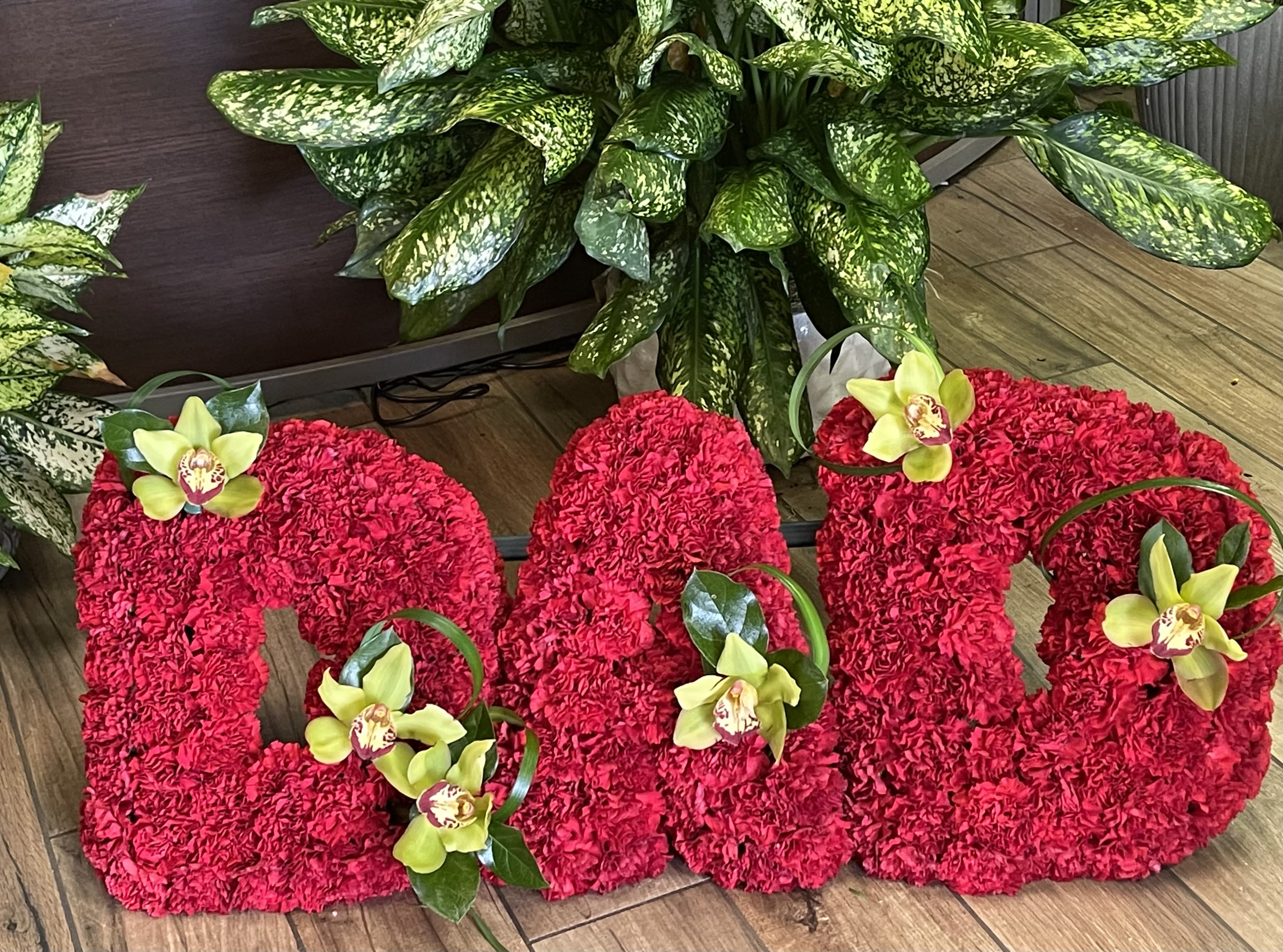 Large red floral letters decorated with yellow orchids