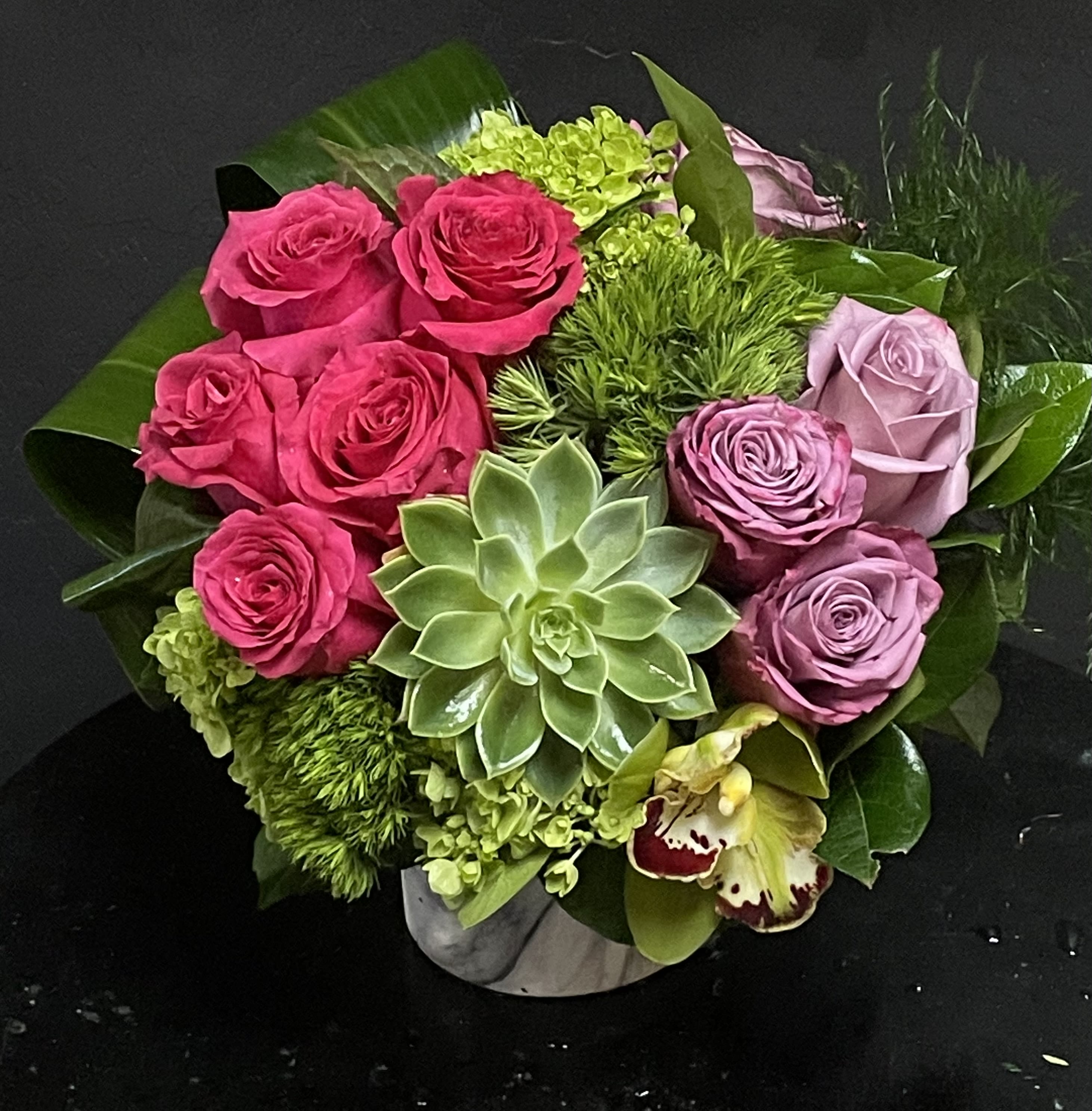 Bouquet of pink and lavender roses with a succulent in a low vase